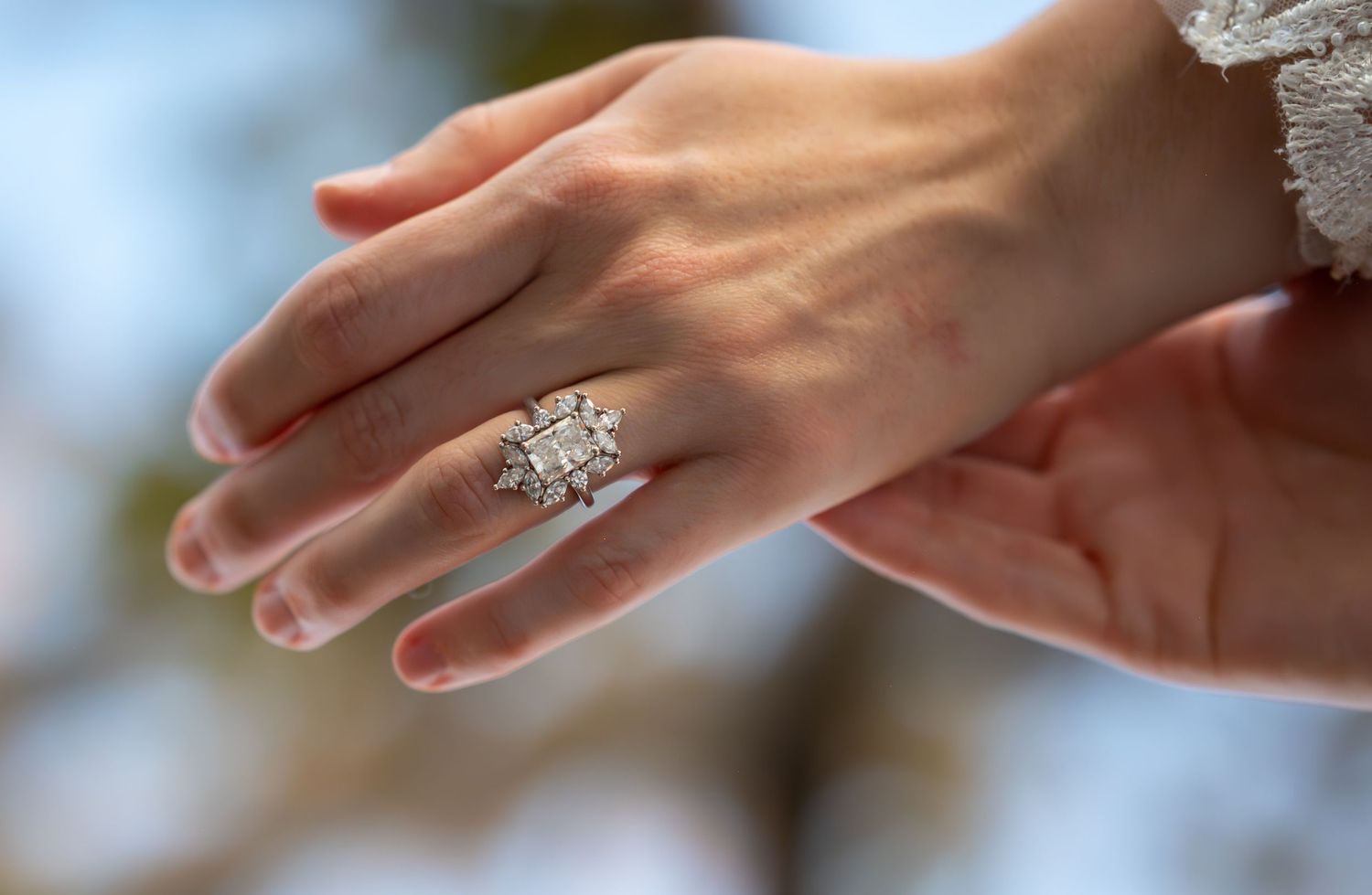 Close-up details of delicate hands and wedding jewelry against soft natural lighting.