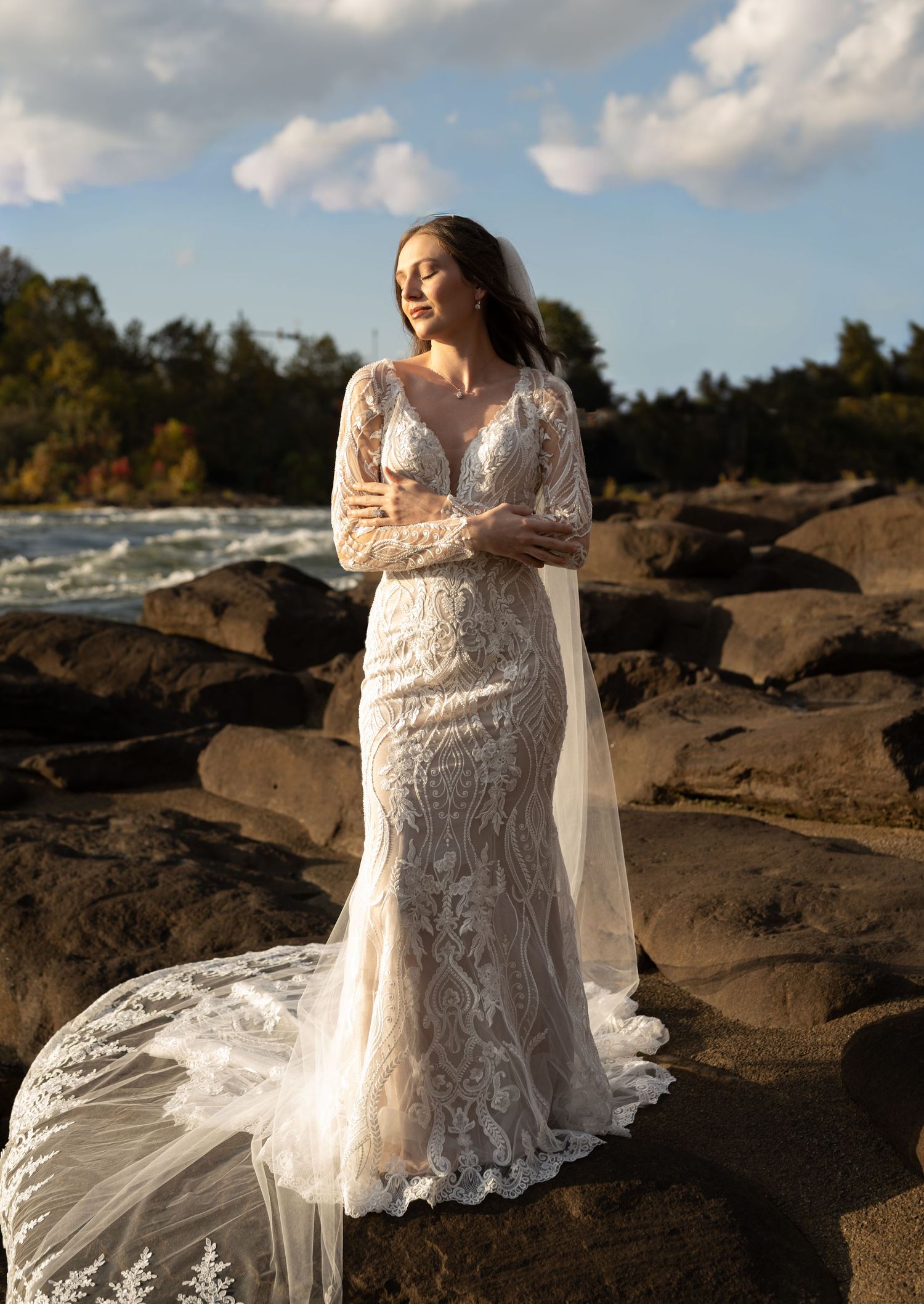 An elegant bridal portrait on rocky terrain with flowing veil and lace gown.