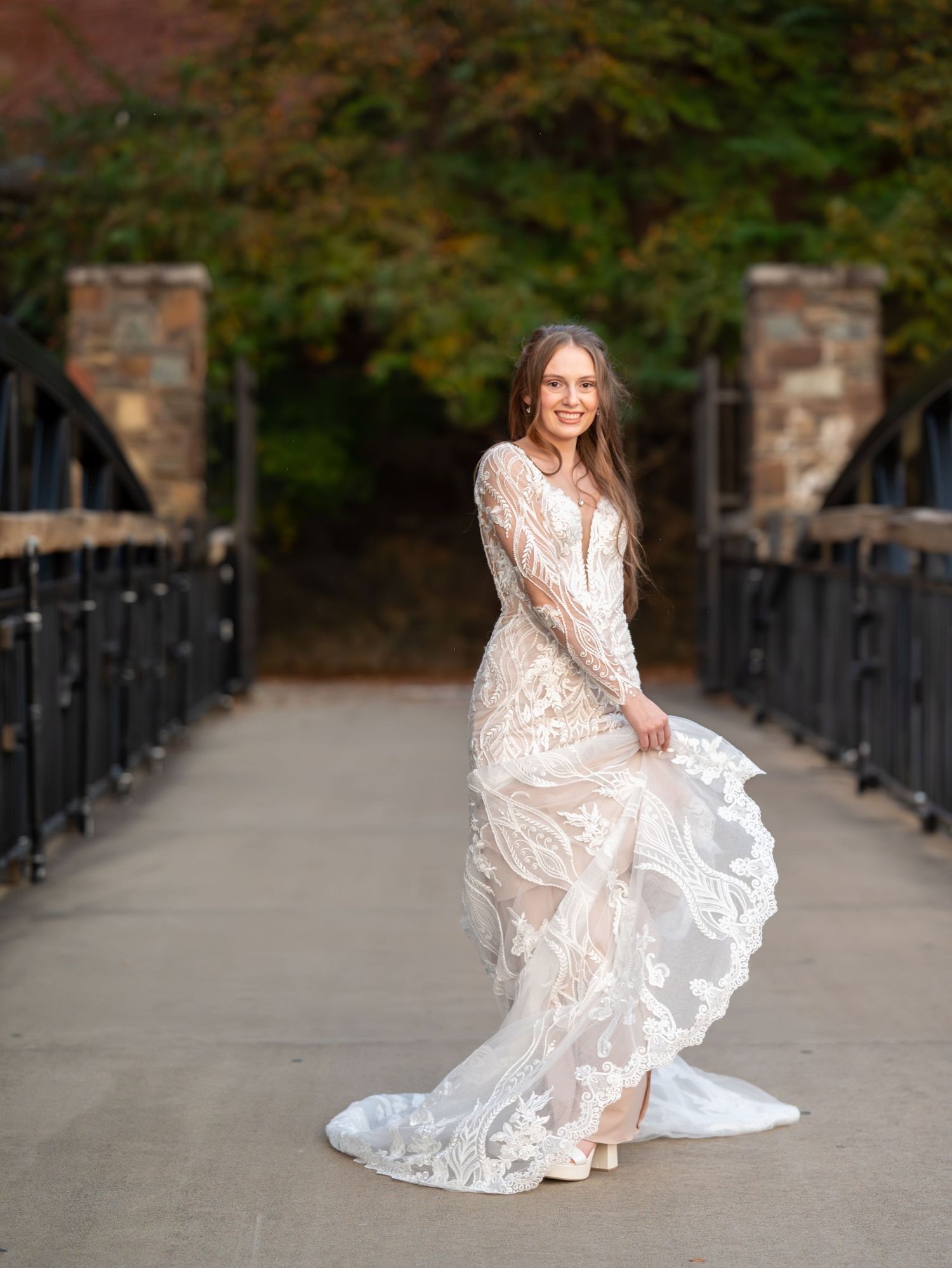 Bridal photography on stone pathway with flowing lace dress and natural fall foliage.