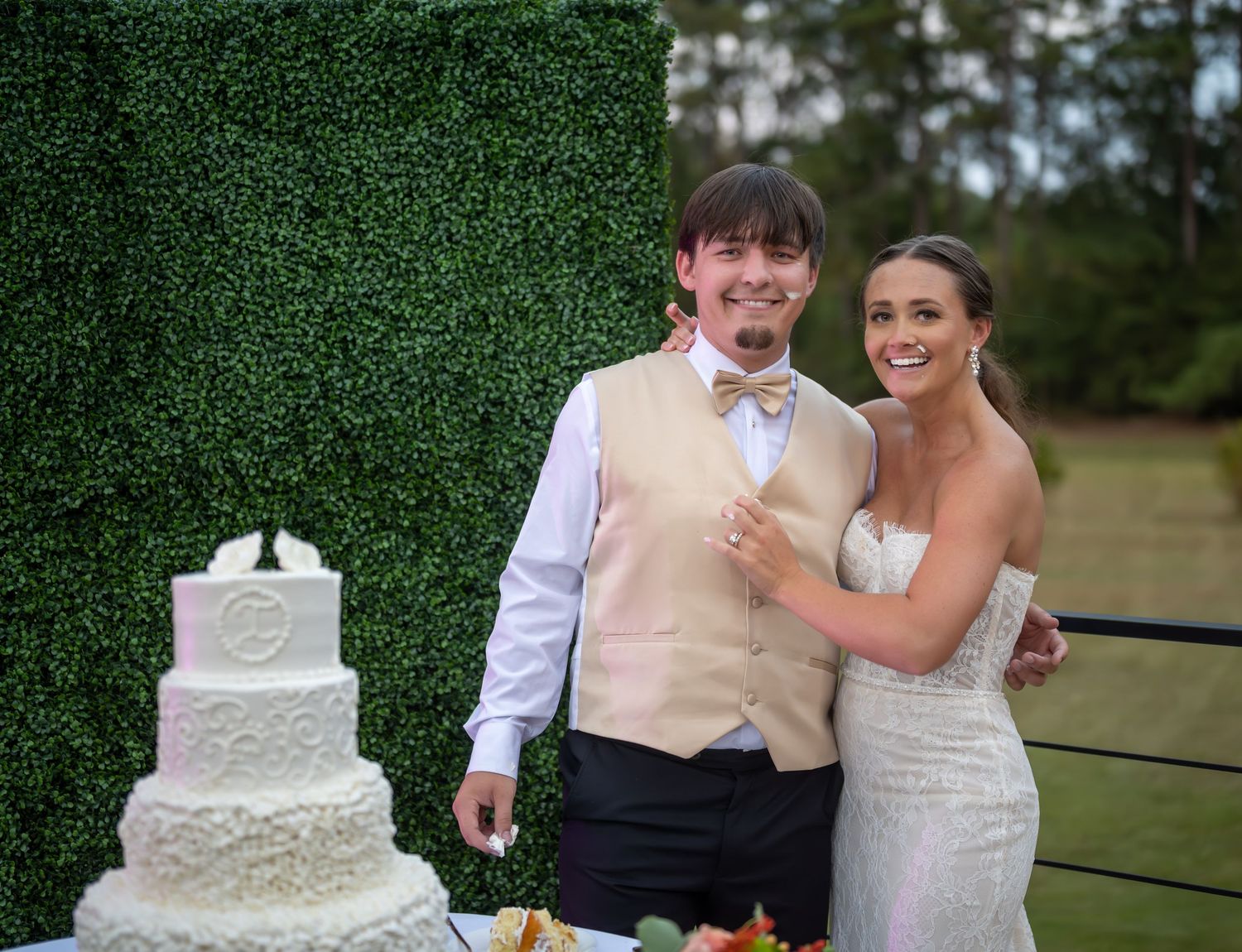 Wedding couple cutting their traditional white tiered cake together at the reception.