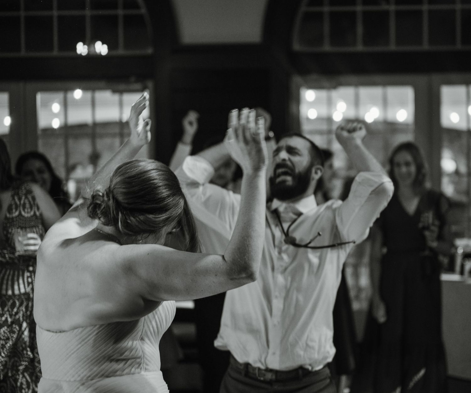 Evening wedding reception features silhouettes of dancers against dim lighting.