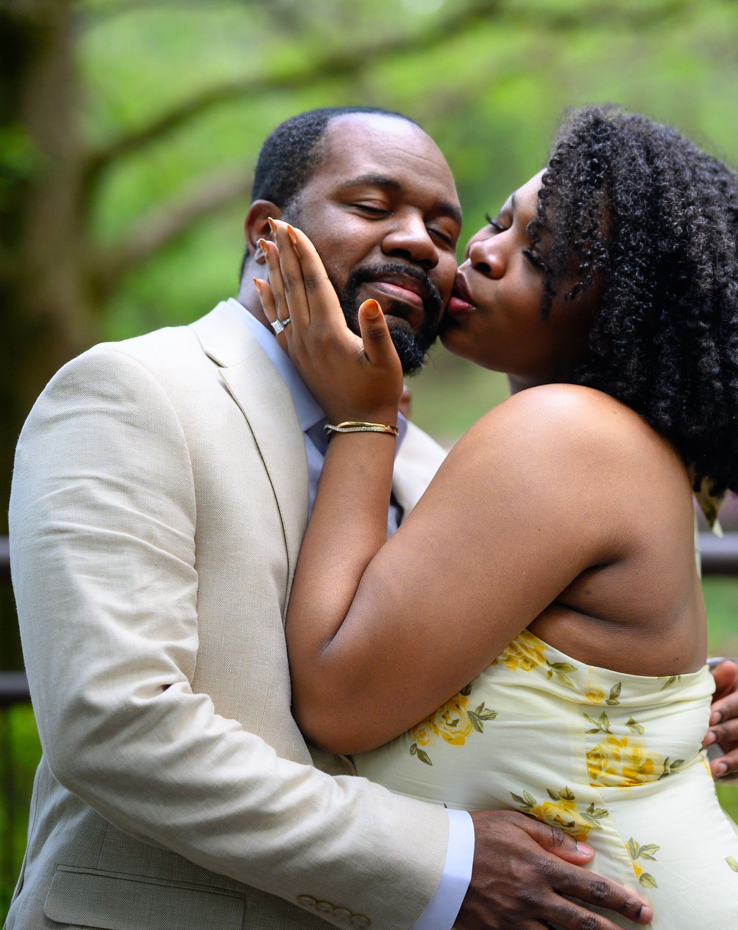 Close-up of a joyful couple sharing a kiss, woman in yellow floral dress embracing mans face tenderly.