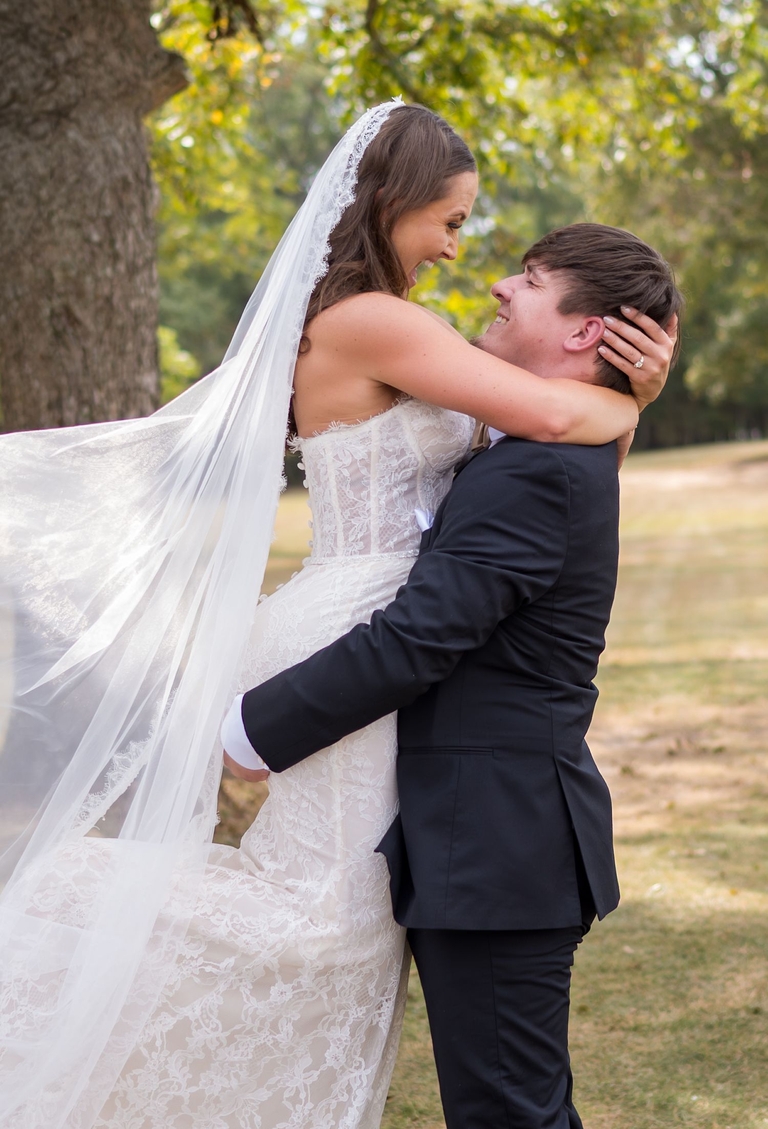 Romantic outdoor wedding portrait with flowing veil and natural autumn backdrop.