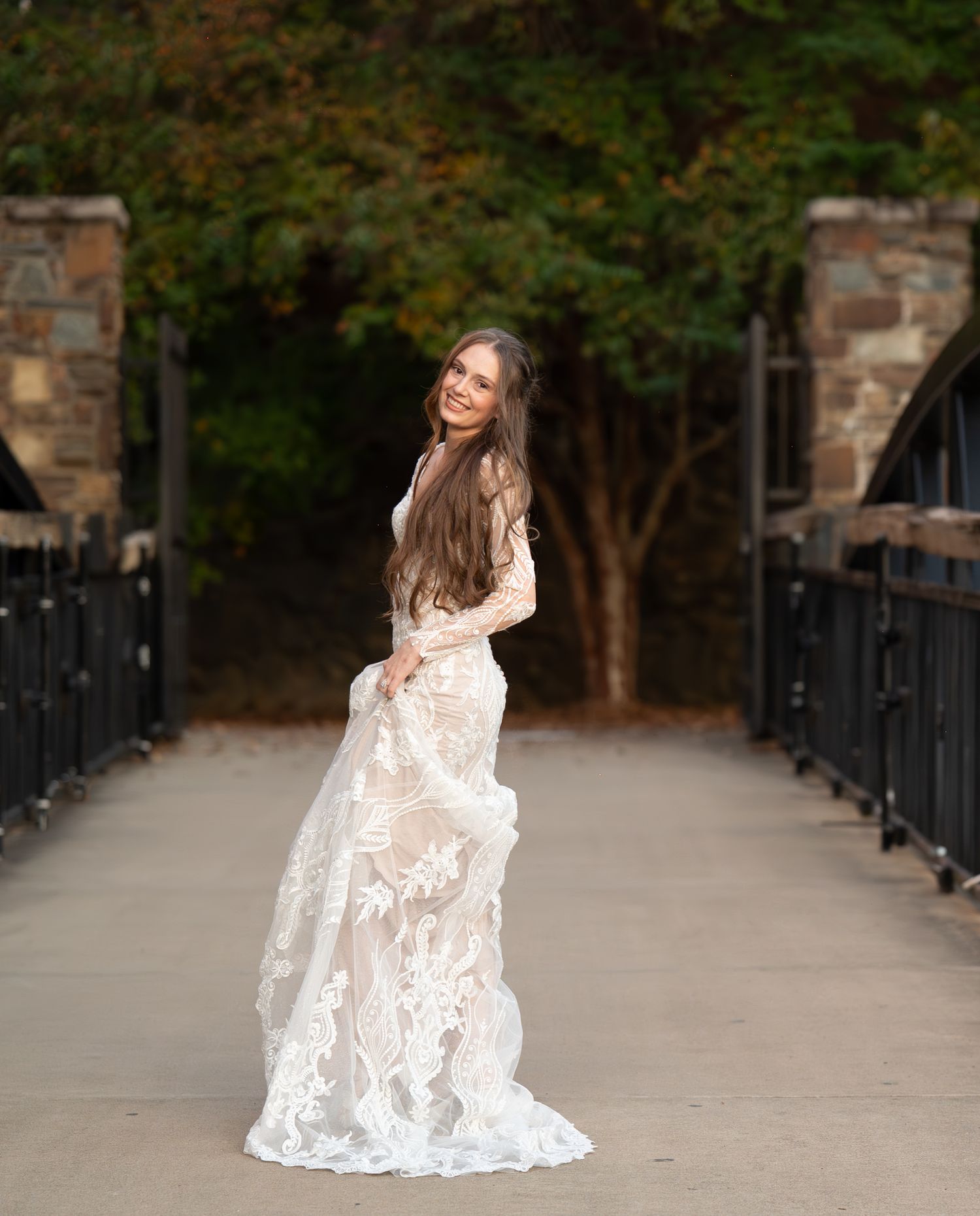 Romantic bridal portraits on pathway with autumn foliage and iron fence backdrop.