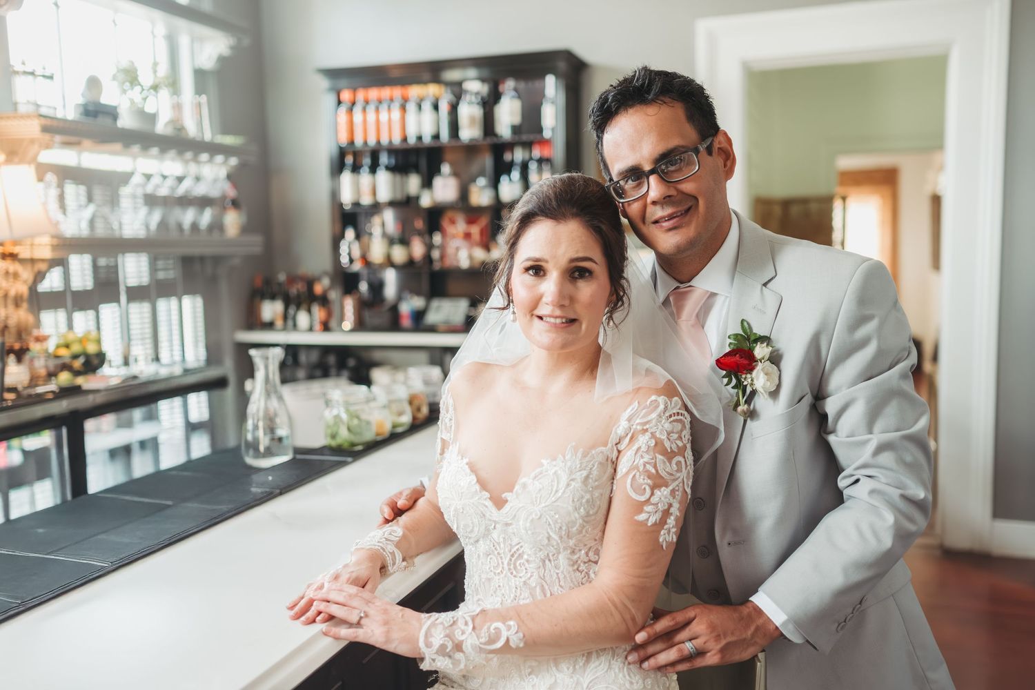 A couple sits together at a bar counter sharing drinks and smiles in a bright restaurant setting.