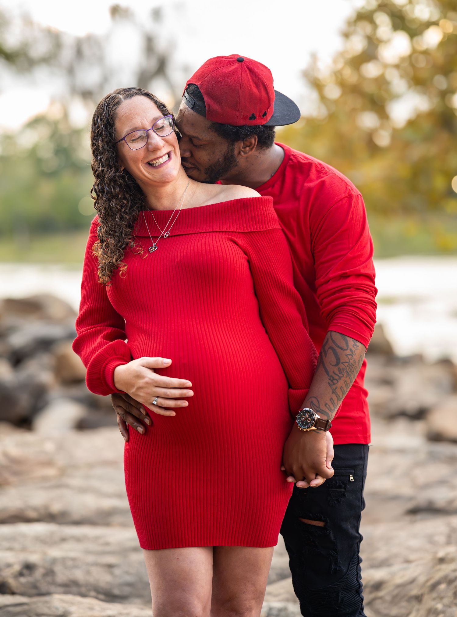 A couple shares an intimate moment on rocky terrain wearing coordinated red outfits.