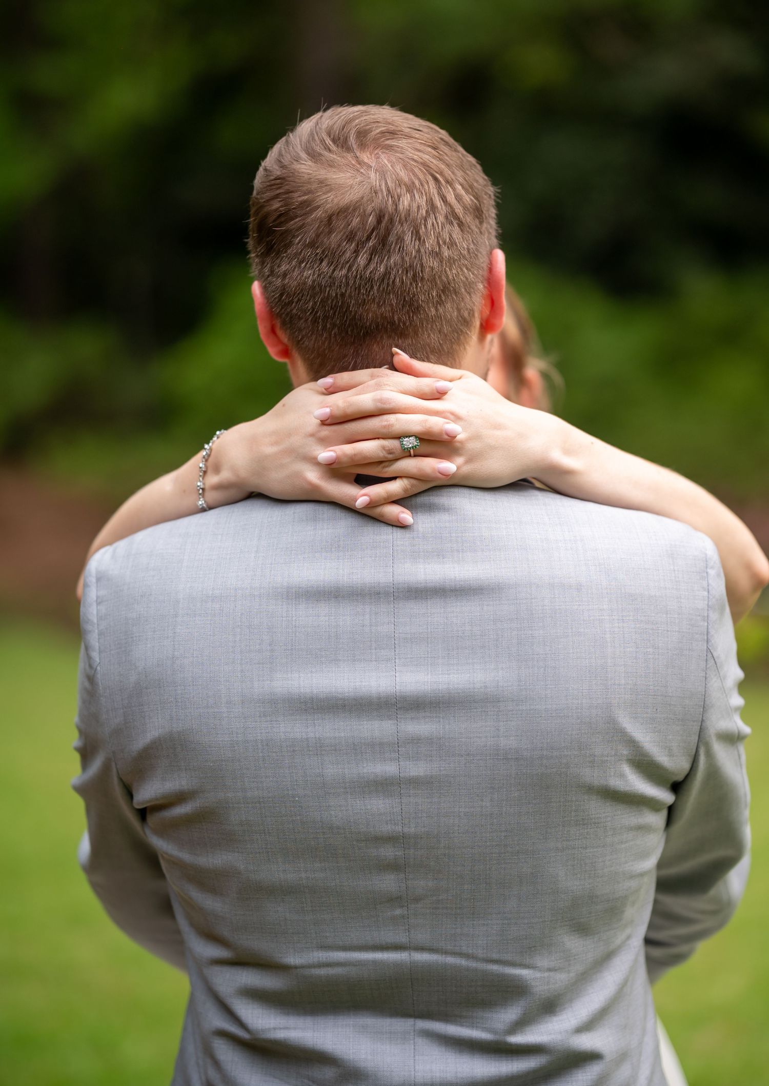 Back view of a person wearing a light grey suit jacket outdoors.