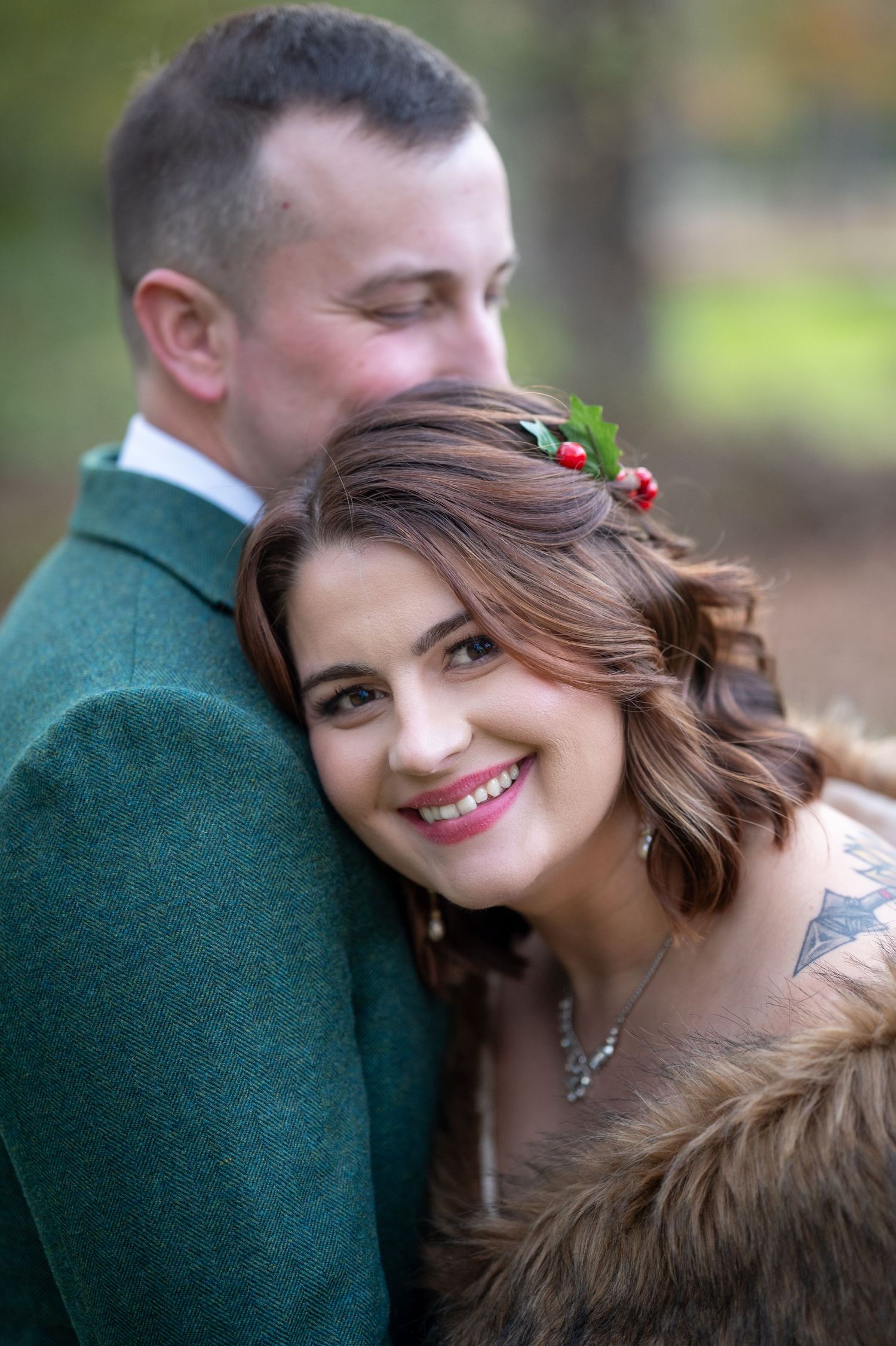 Wedding couple embracing outdoors with bride wearing fur wrap and floral crown.