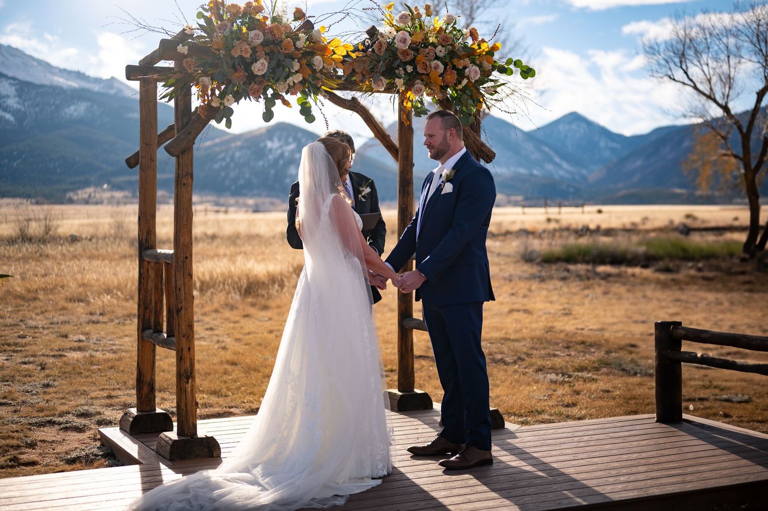 Series of wedding moments under rustic wooden arch with mountain landscape at the Barn at the Sunset Ranch wedding venue in Buena Vista, CO.