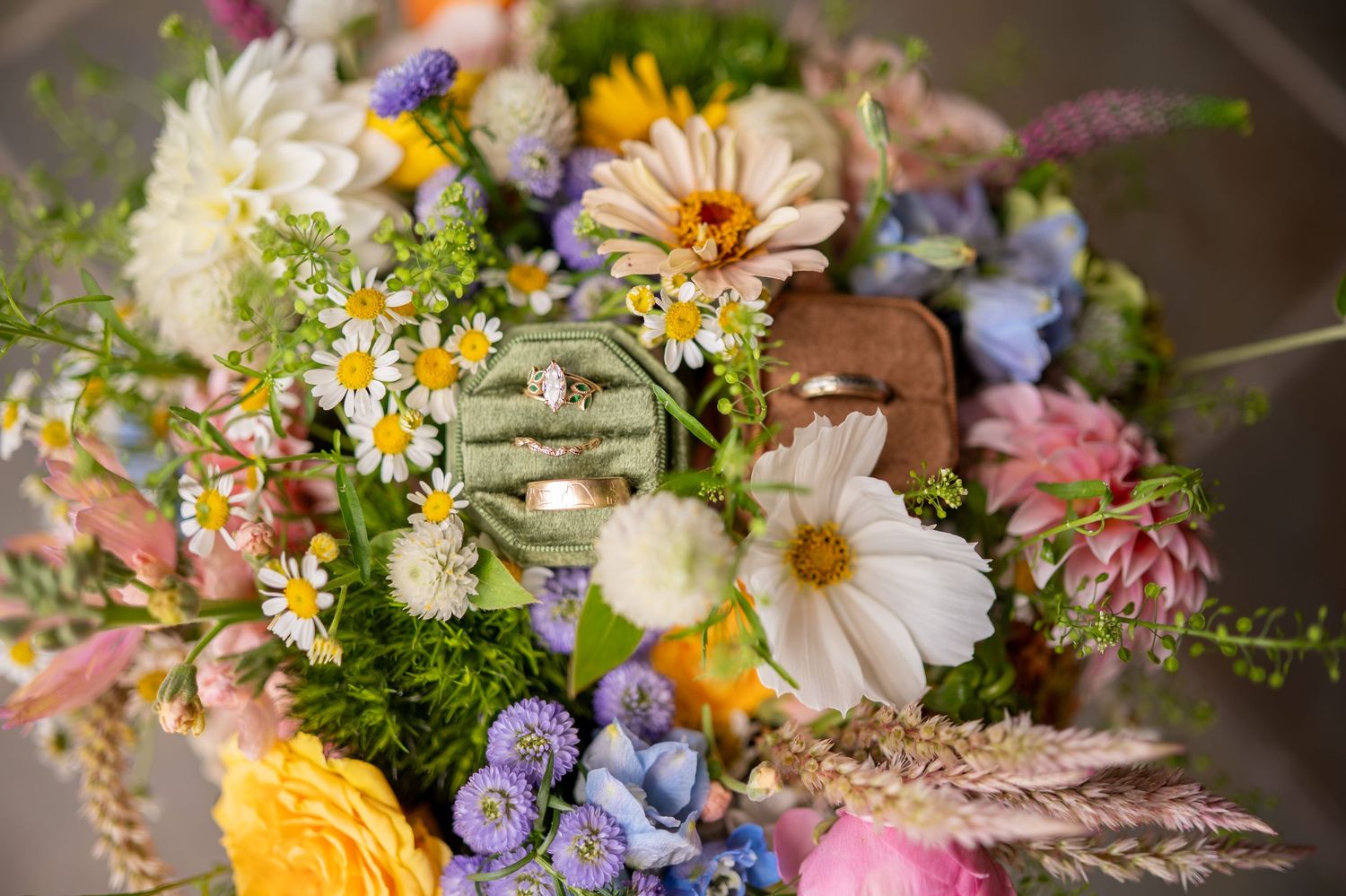 Colorful wildflower bouquet with daisies, blue delphinium, and pink blooms arranged in rustic farmhouse style.