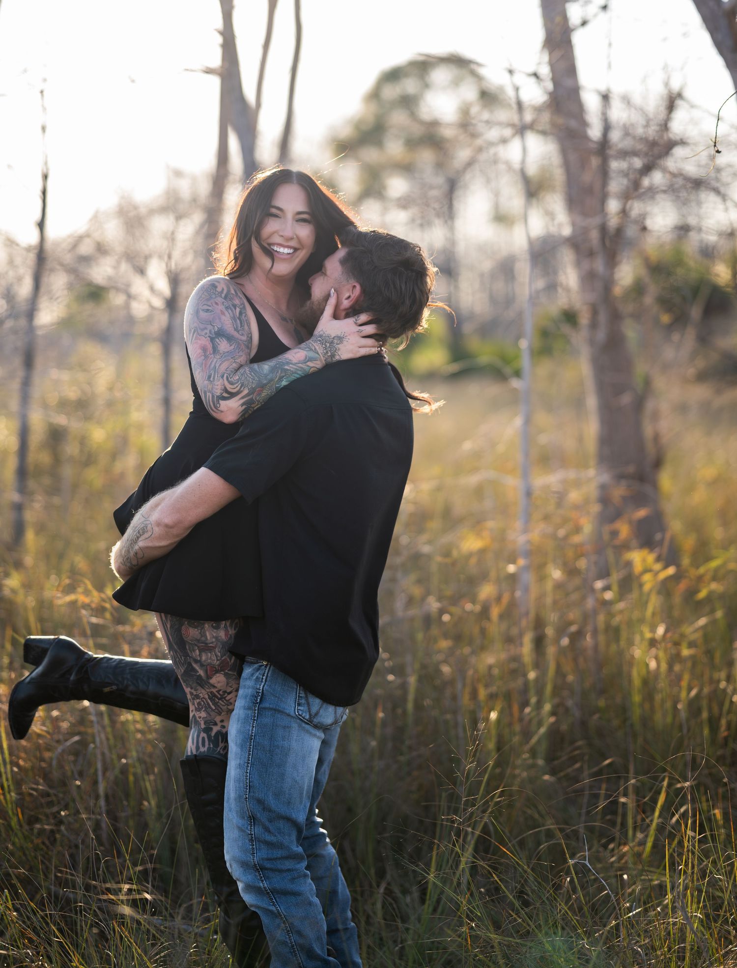 Couple shares intimate moments and laughter while standing in a natural grass field.