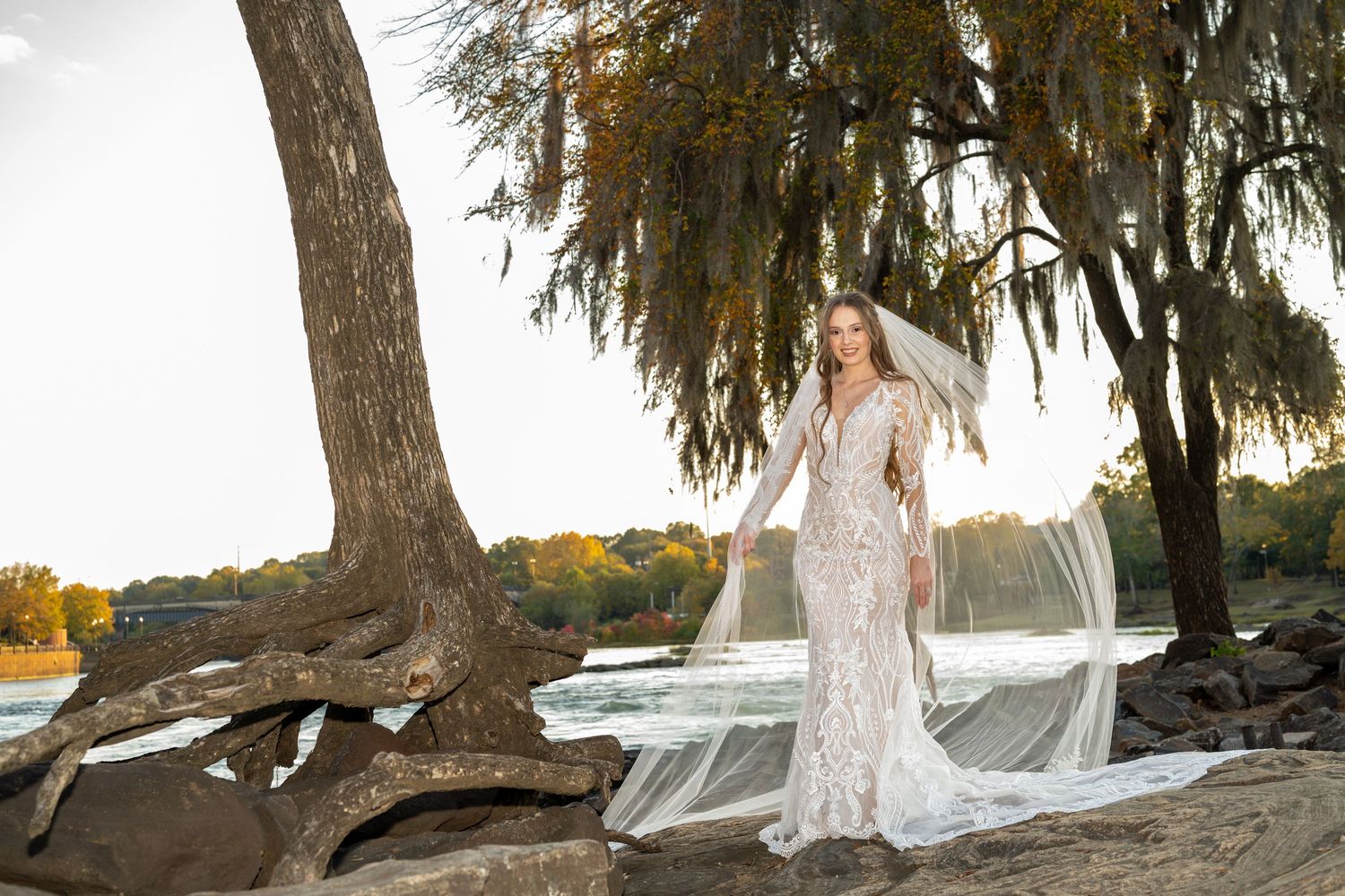Scenic waterfront bridal portraits under willow trees at sunset.