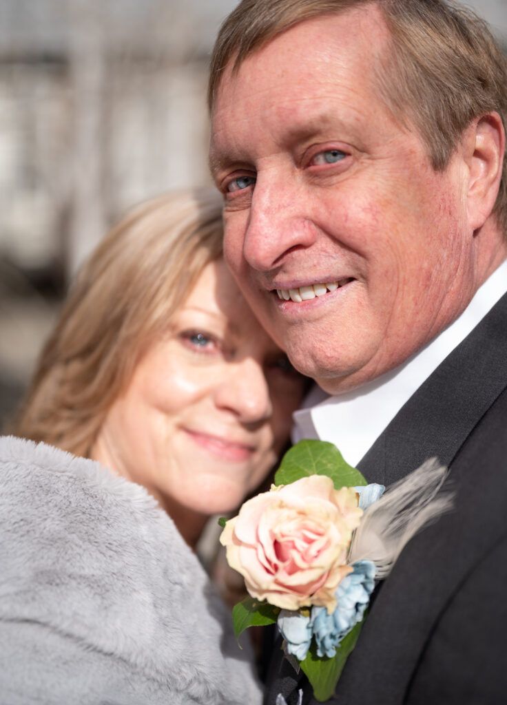 Senior Couple, Bride & Groom, embracing. The brides face is resting on the grooms shoulder at their elopement in Colorado. Both are smiling.