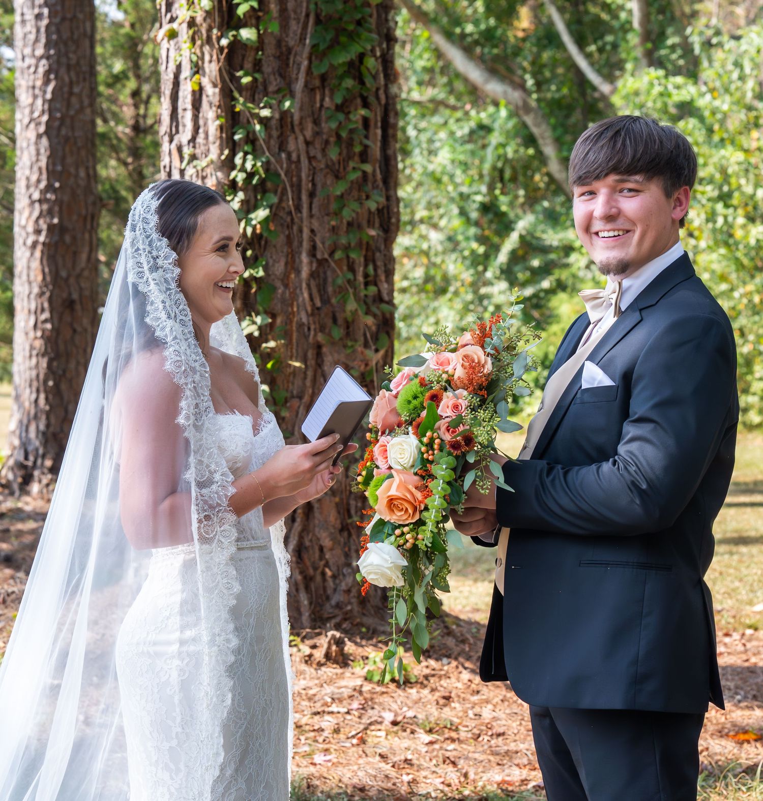 Wedding couple shares romantic moments in a wooded setting with fall foliage.