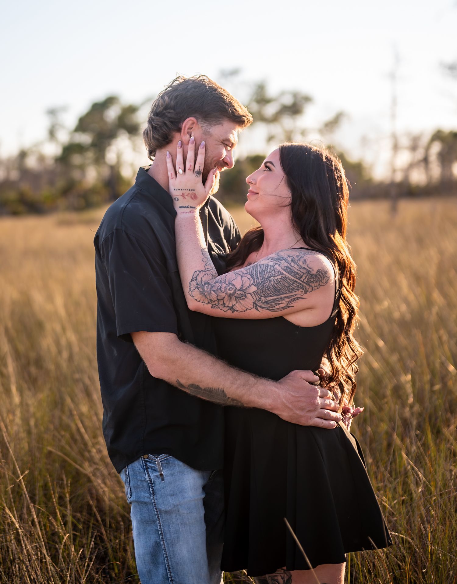 Affectionate couple sharing romantic moments in a field during golden hour.