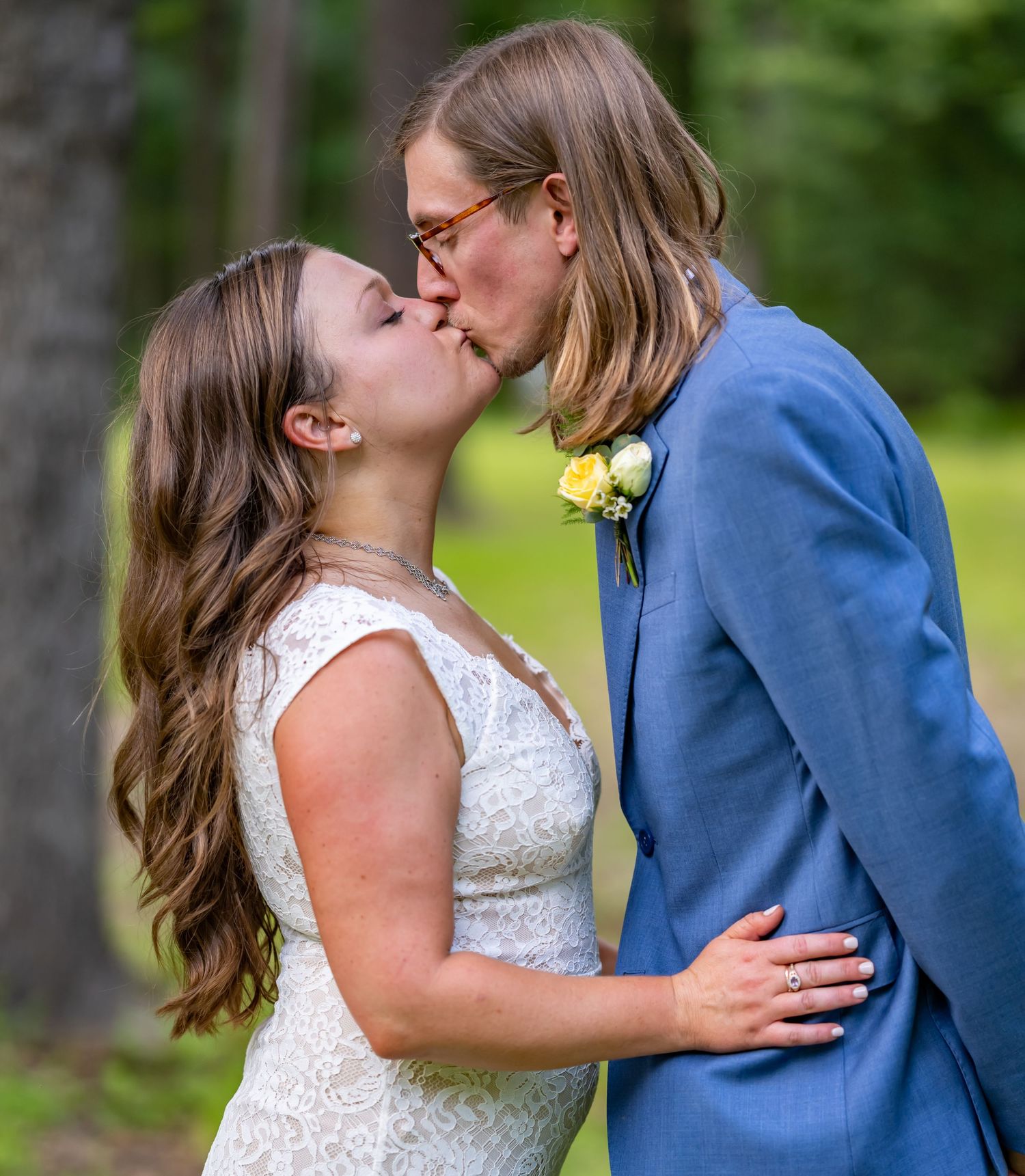 Tender wedding moment captured in vibrant garden setting with natural greenery.