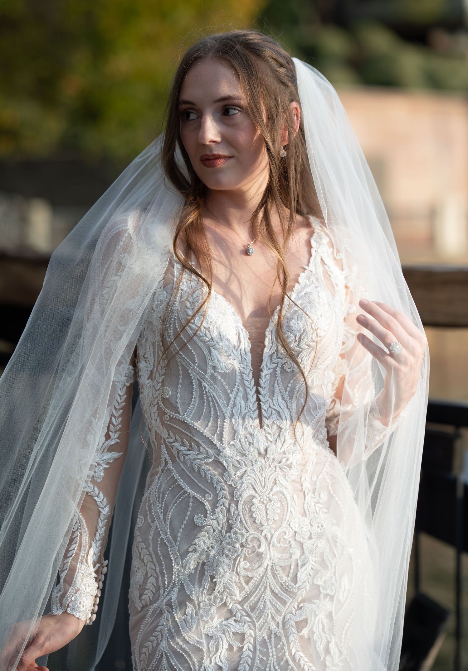 Close-up of intricate lace wedding dress details with ethereal veil in natural lighting.