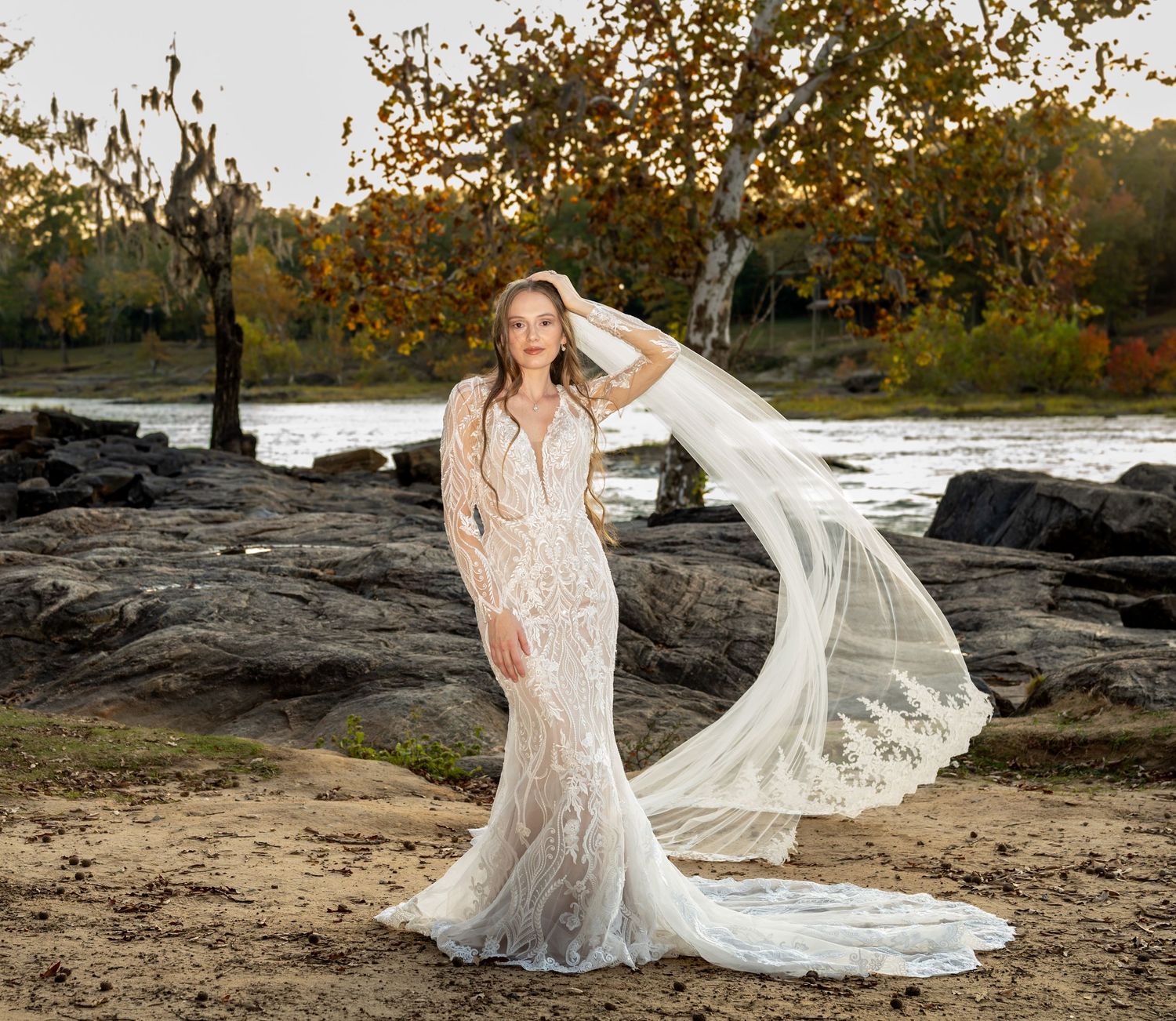 Waterfront bridal portraits with long veil flowing in autumn scenery.