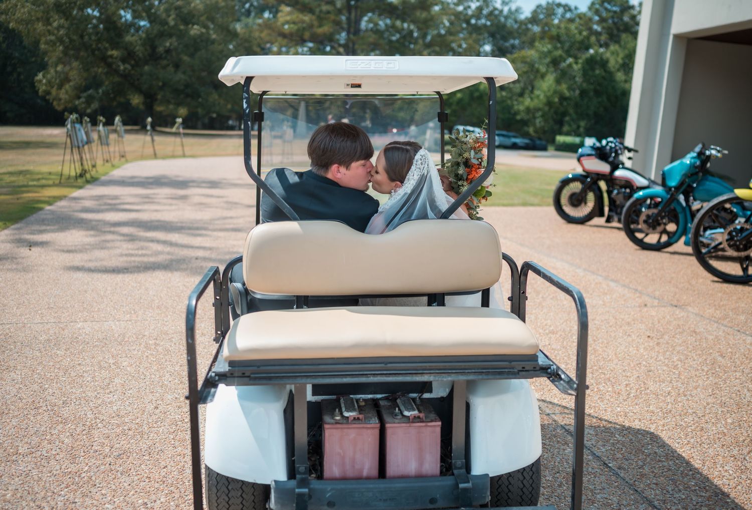 Row of golf carts parked on a gravel path at a country club or golf course.