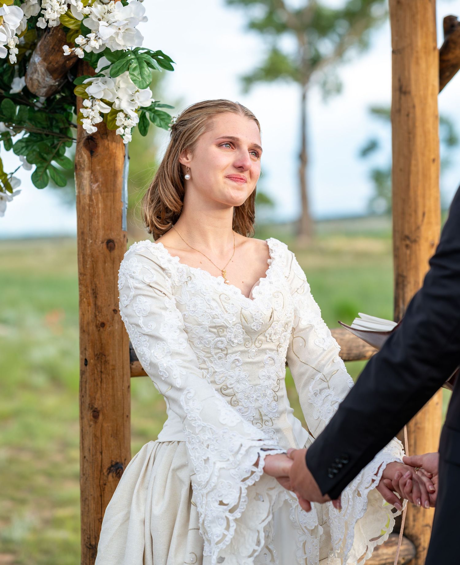 Wedding ceremony details showing white floral arrangements on wooden posts.