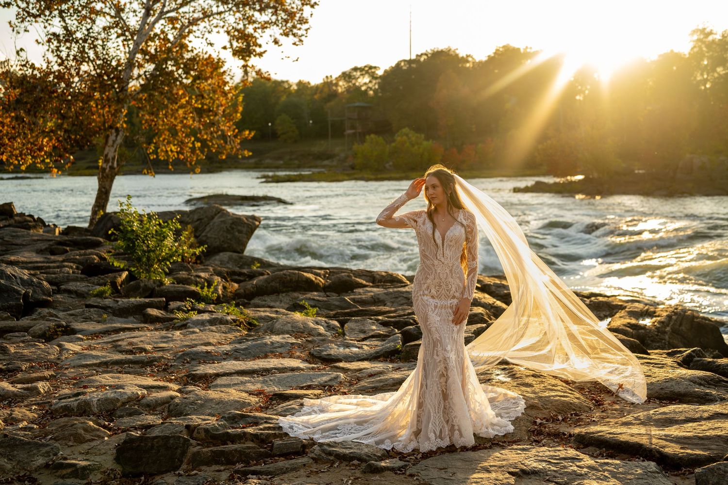 Dramatic bridal portraits on rocky coastline during golden hour with flowing veil.