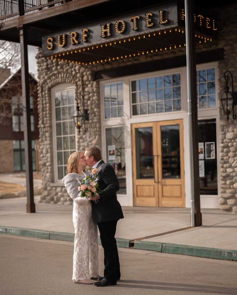 Senior bride and groom dancing and embracing in front of the Surf Hotel. The couple looks in love and happy after their recent elopement.