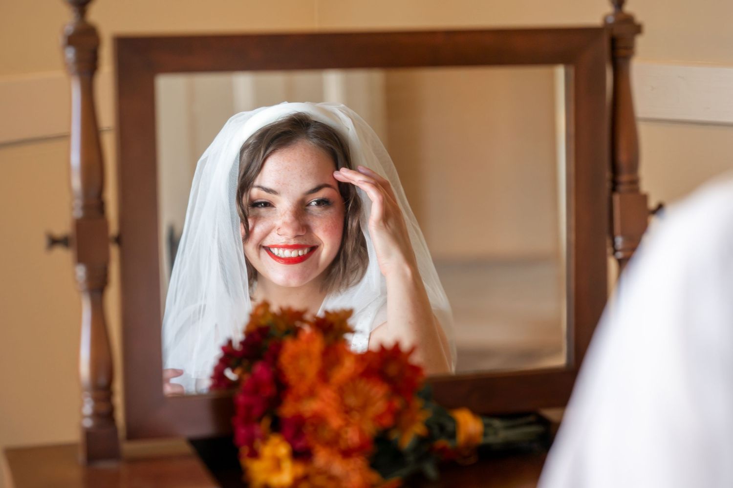 A wedding portrait composition showing a person in a white dress with autumn flowers at a rustic wooden interior venue.