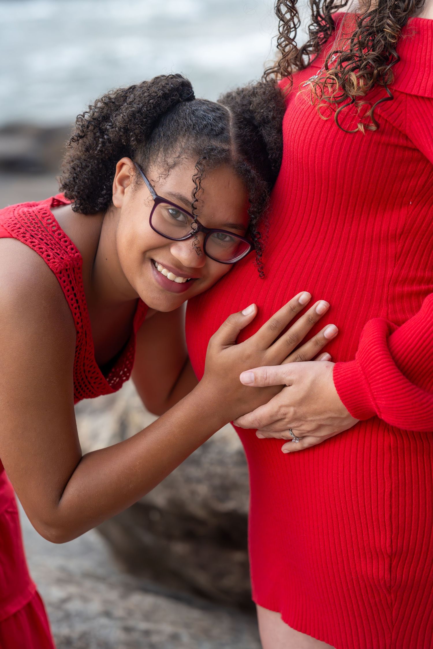 Tender moment captured against rocky backdrop as two people in red embrace.