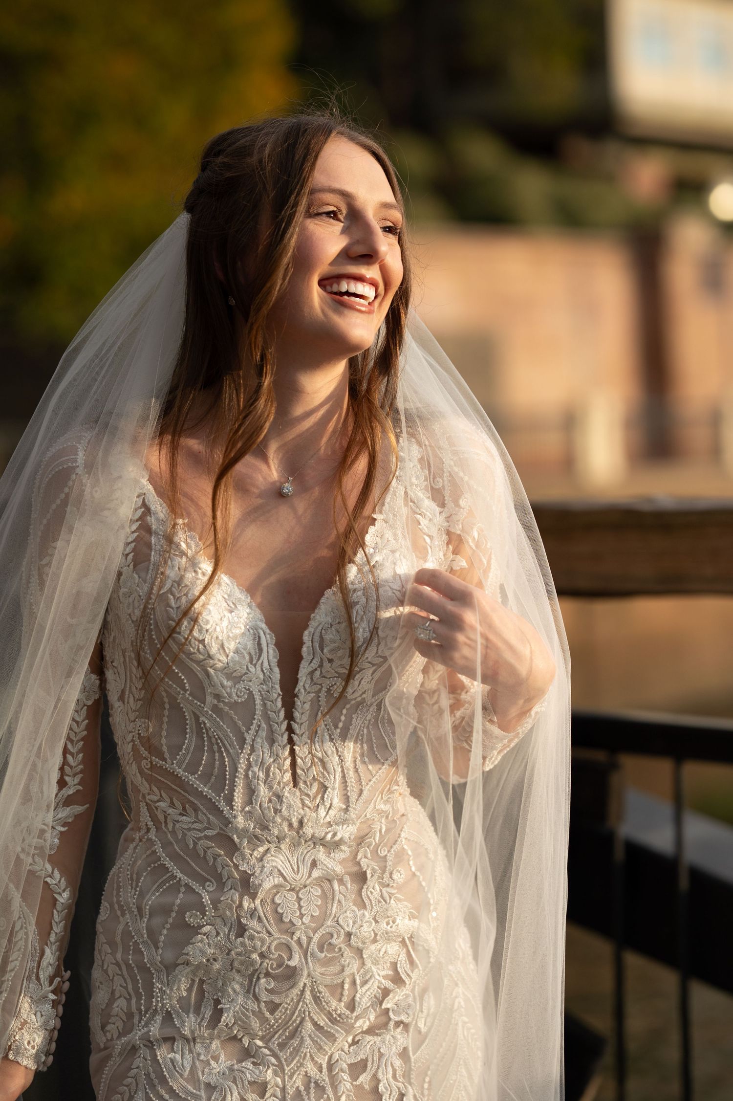 Elegant lace wedding gown with detailed embroidery shown in warm golden light.