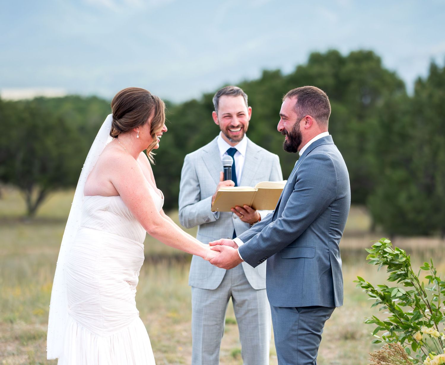 Outdoor wedding ceremony with a couple exchanging rings on a sunny day.