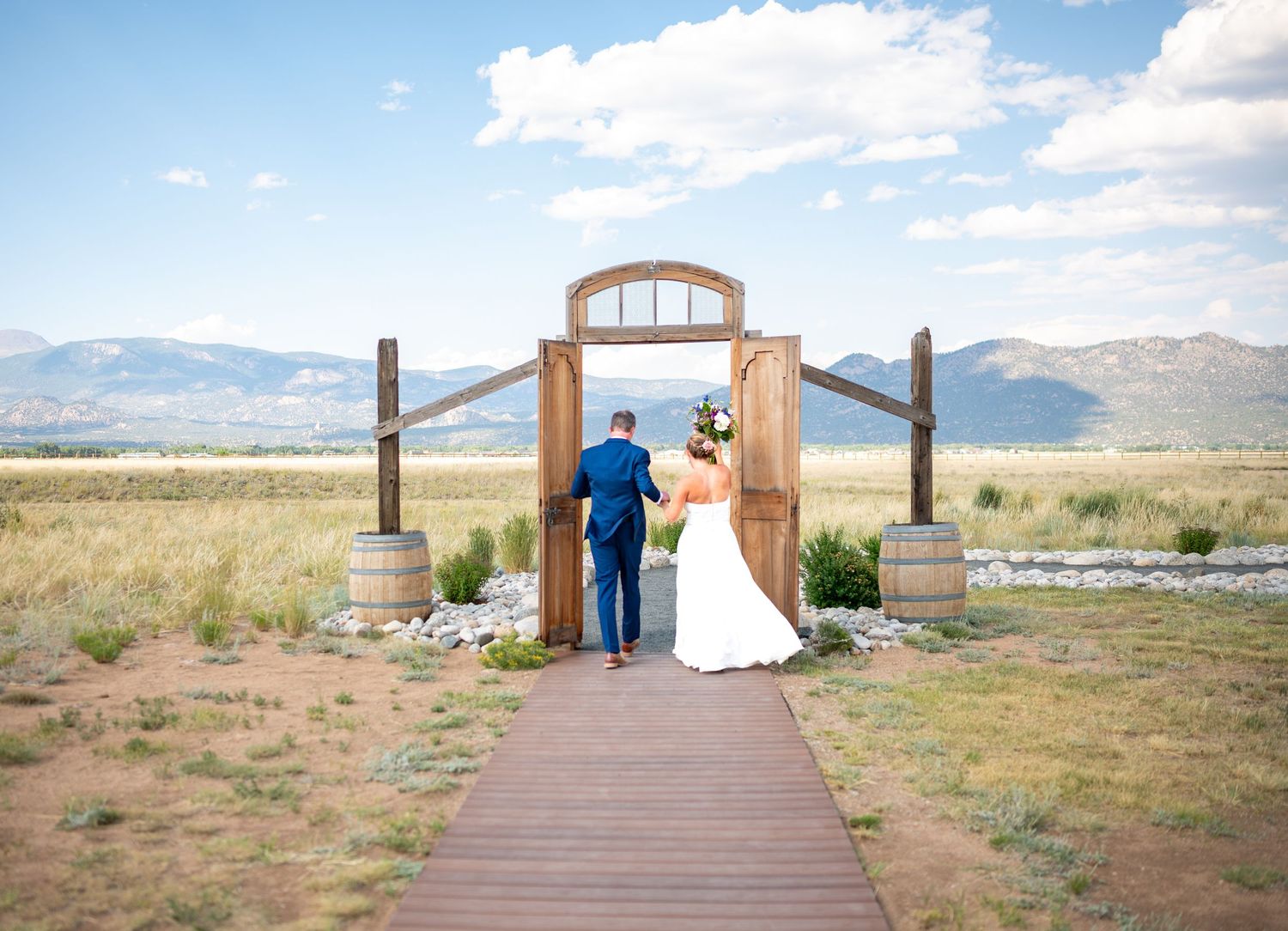 Panoramic view of outdoor wedding venue with mountainous landscape and wooden walkway a the Barn at Sunset Ranch wedding venue in Colorado.