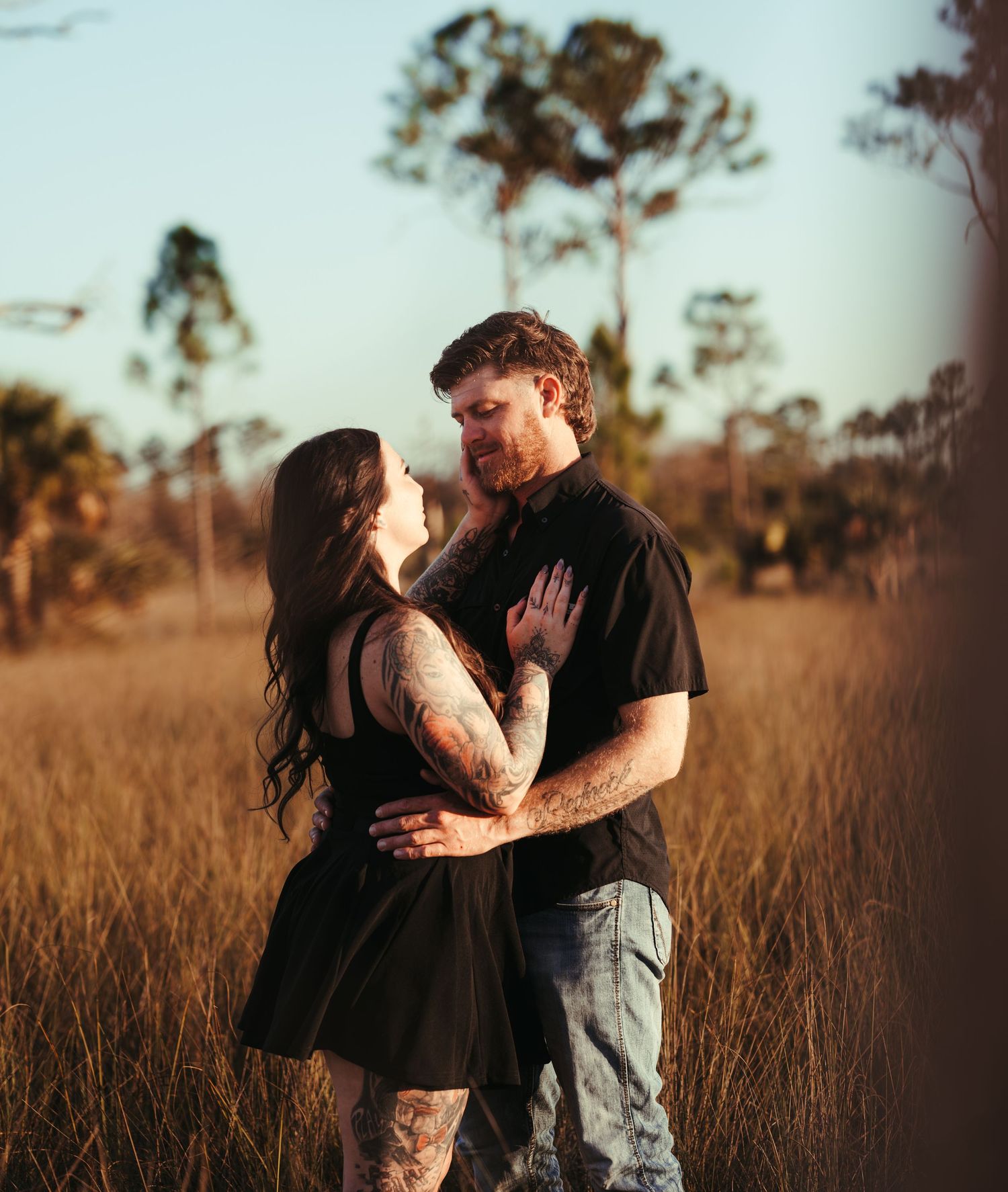 Intimate couple shares tender moments in a rustic field during golden hour.