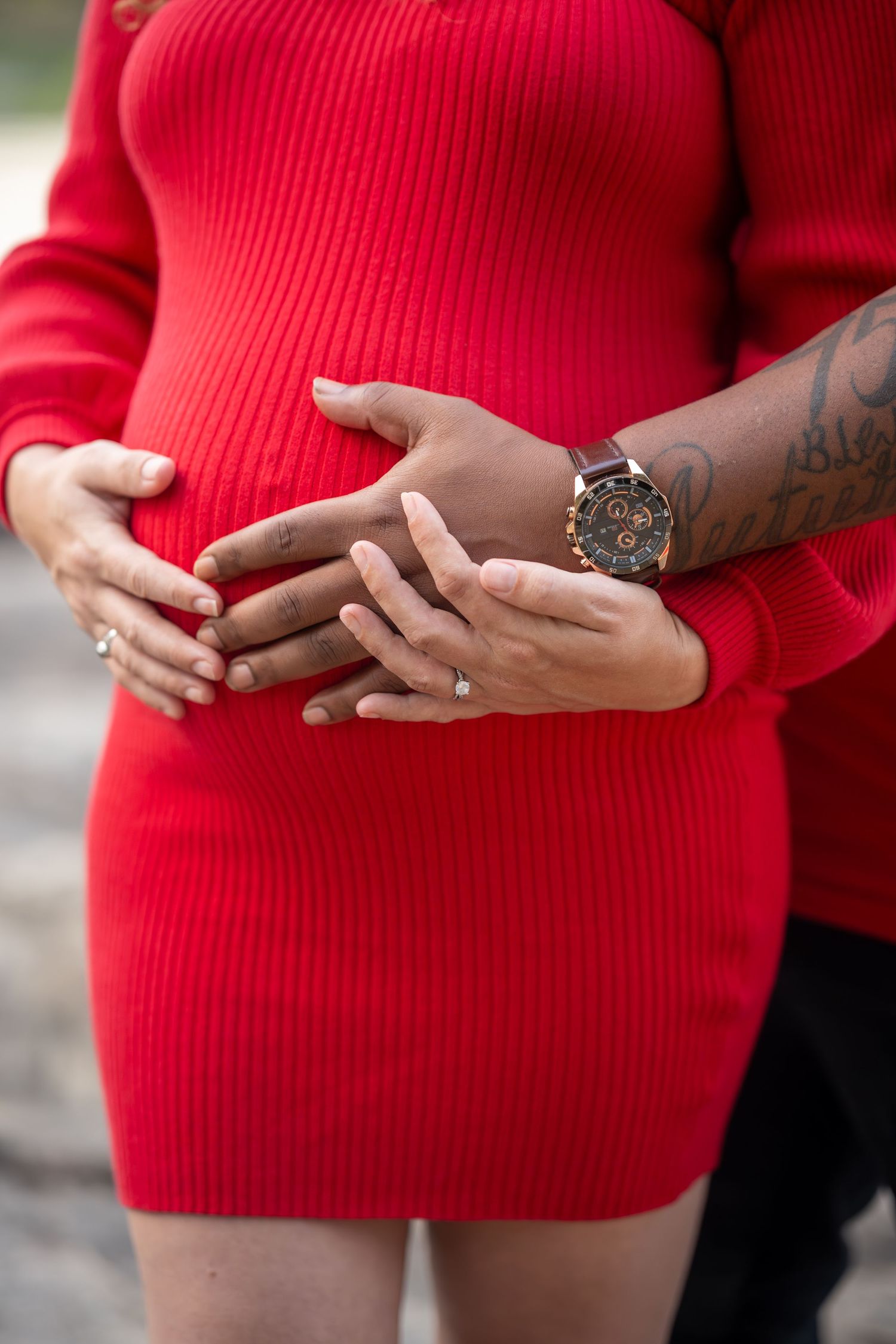 Close-up shots of hands with tattoos against a red sweater background.