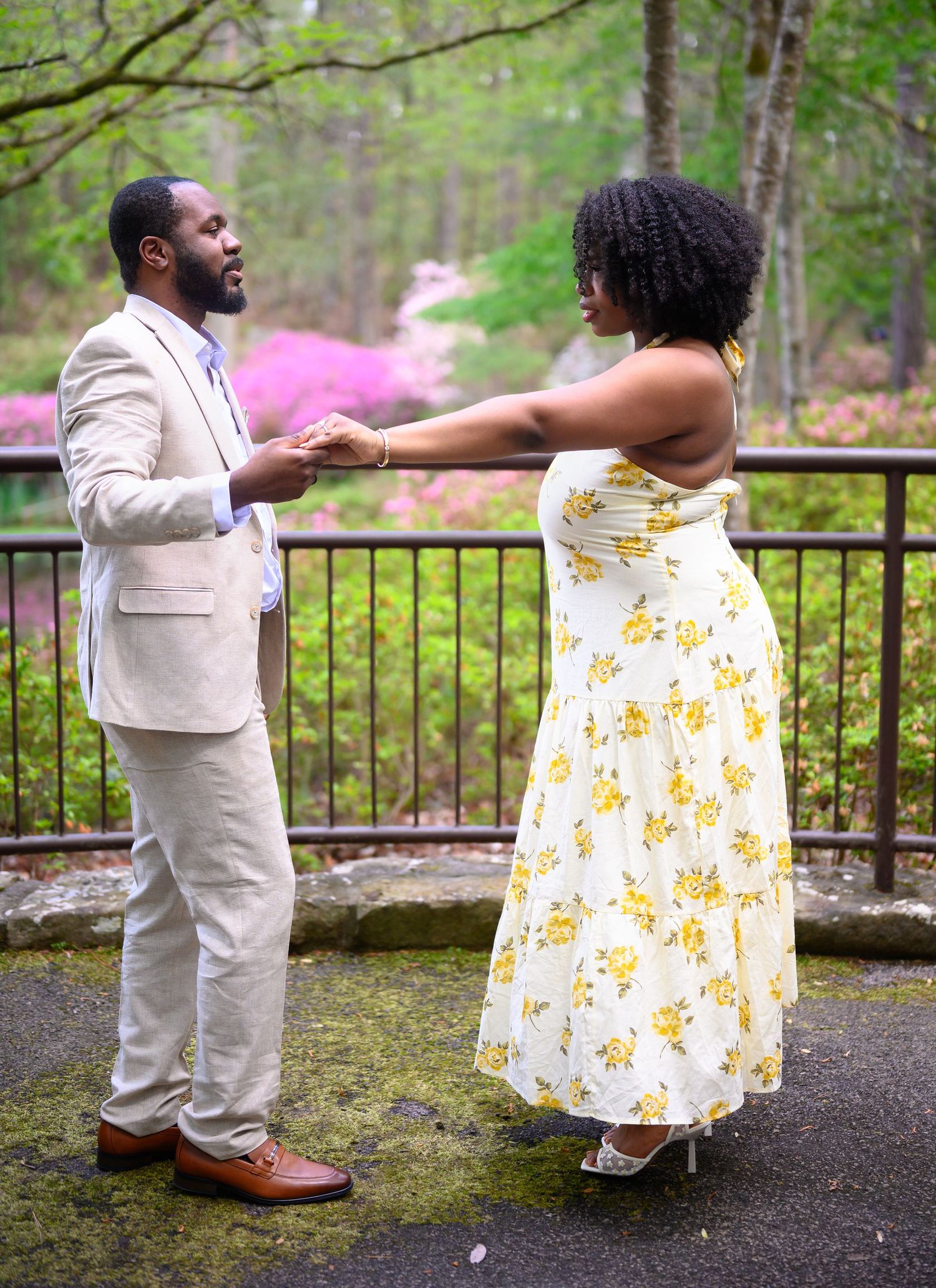 Couple holding hands and gazing at each other on a stone terrace in a garden.