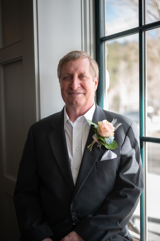 Senior Groom standing in front of a window at the Surf Hotel. The groom is smiling and well lit by the beautiful lighting shining in.