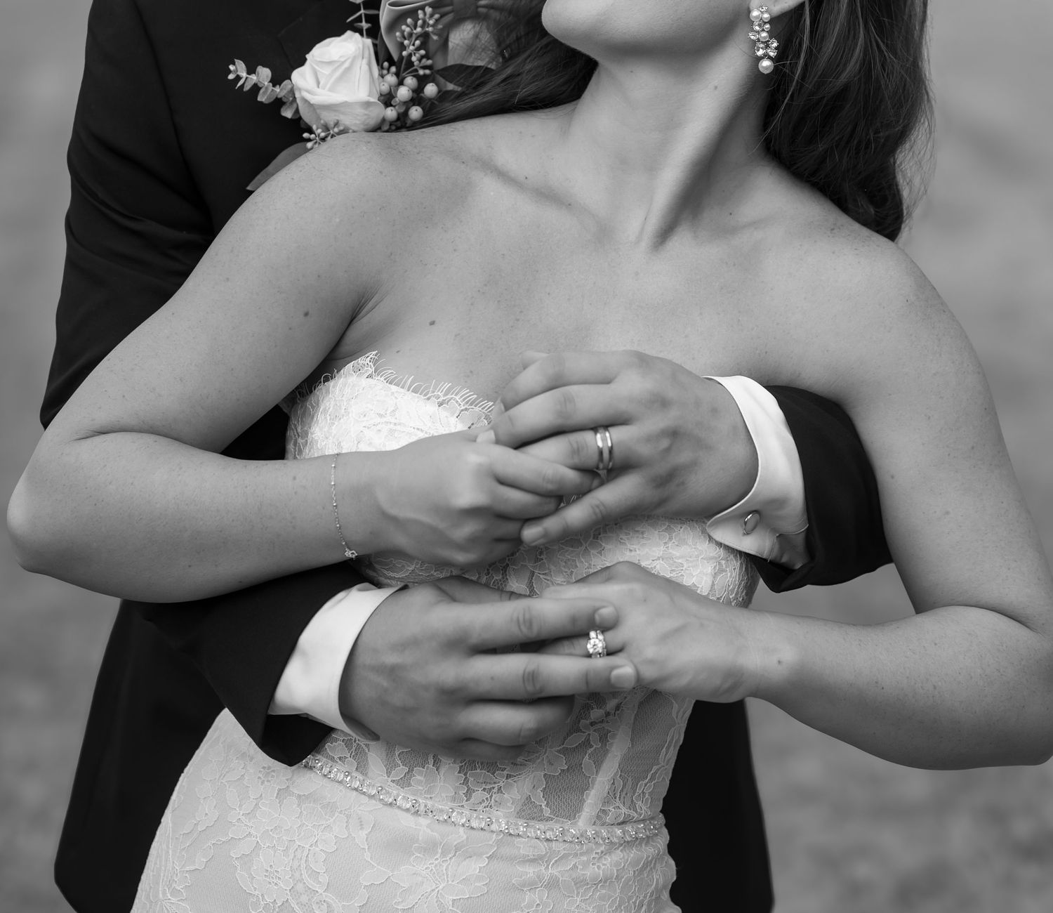 Close-up detail of hands and wedding dress in black and white photography.