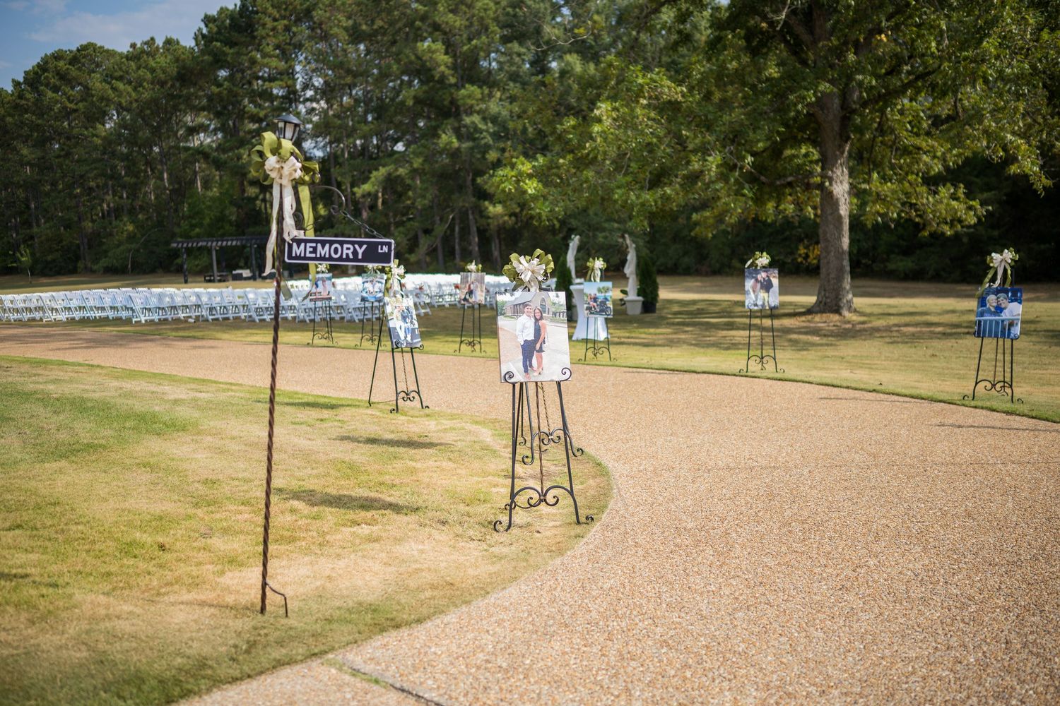 Outdoor venue setup with white chairs and decorative elements arranged in rows on a grassy field.