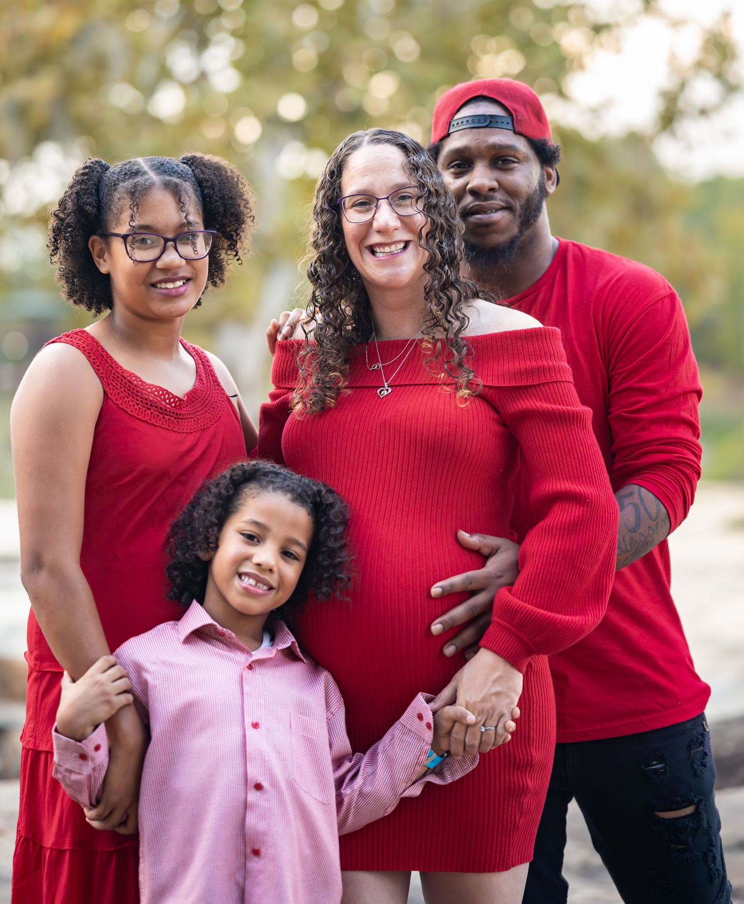 A family dressed in matching red outfits shares joyful moments together in an outdoor setting.