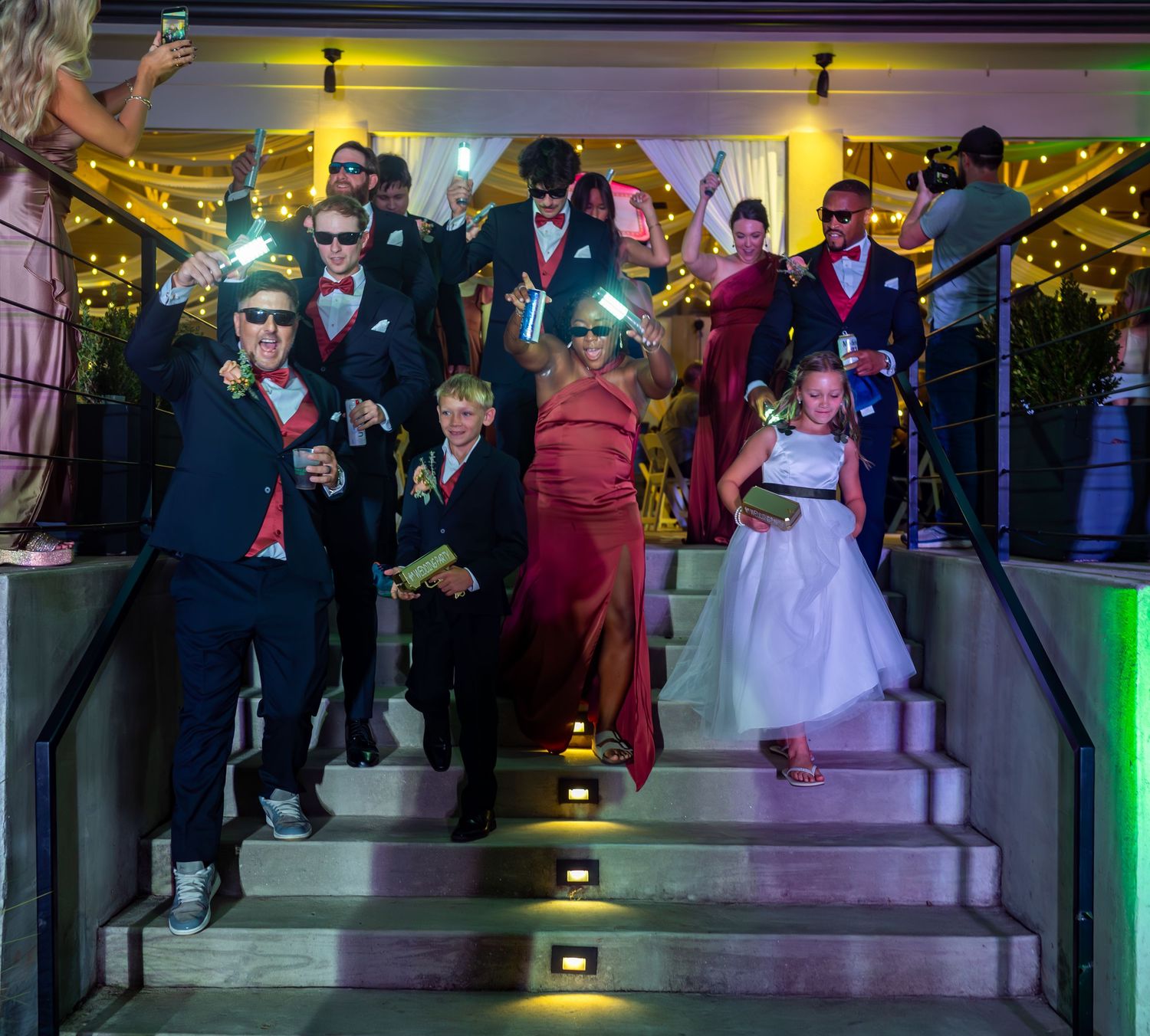 Wedding reception dance floor filled with guests under decorative lighting and streamers.