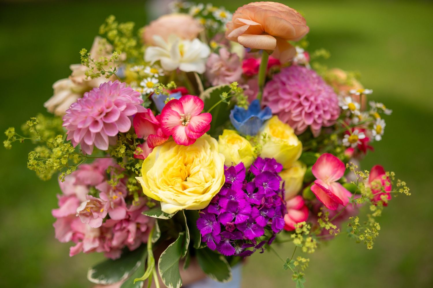 Colorful wedding flower arrangement featuring pink, yellow and purple blooms with greenery.