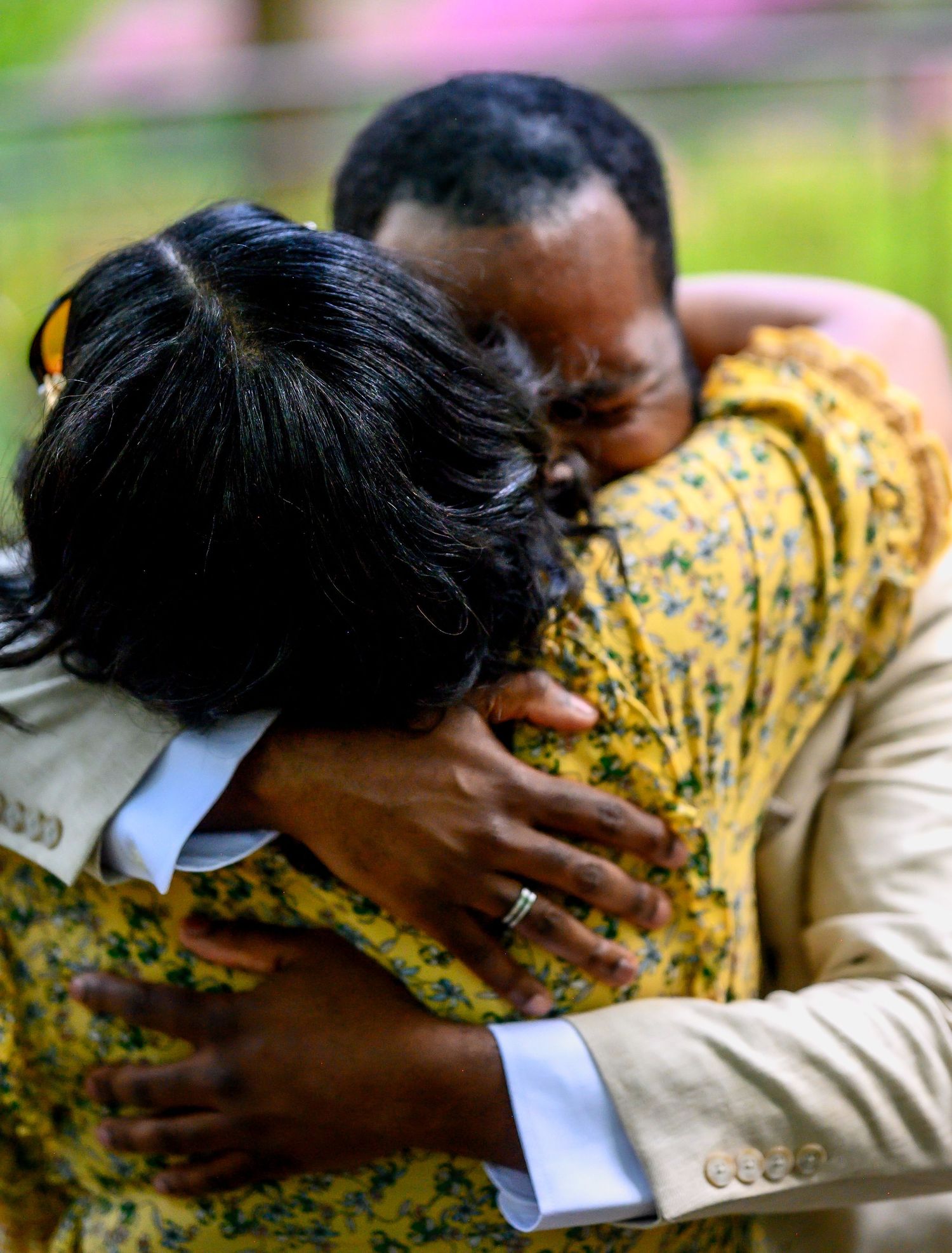 Couple sharing an emotional embrace after a marriage proposal in a beautiful outdoor garden setting.