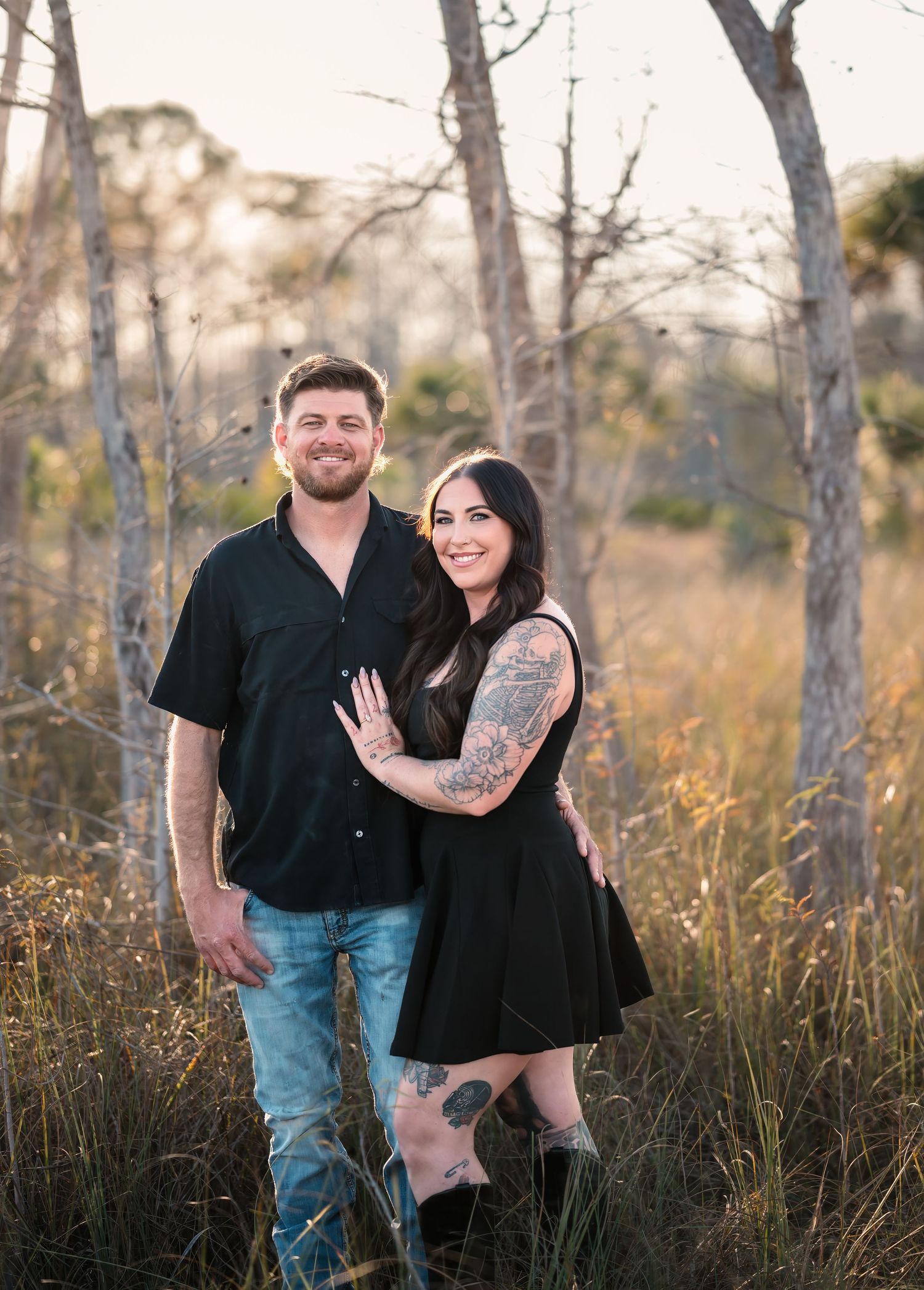 A couple laughs together during their engagement photo session in a rustic outdoor setting.