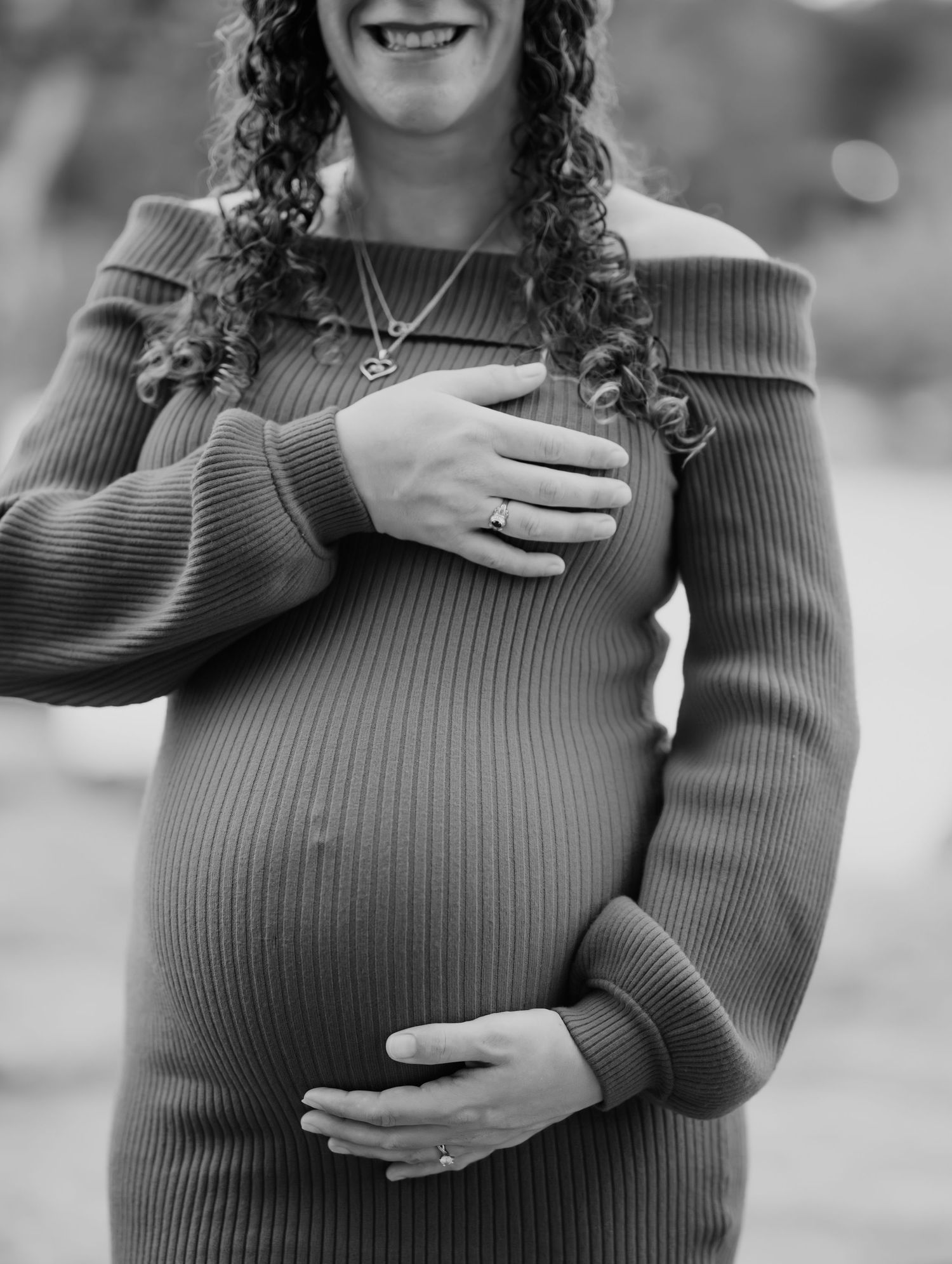 Black and white maternity photos showing close up of pregnant belly with hands placed lovingly.