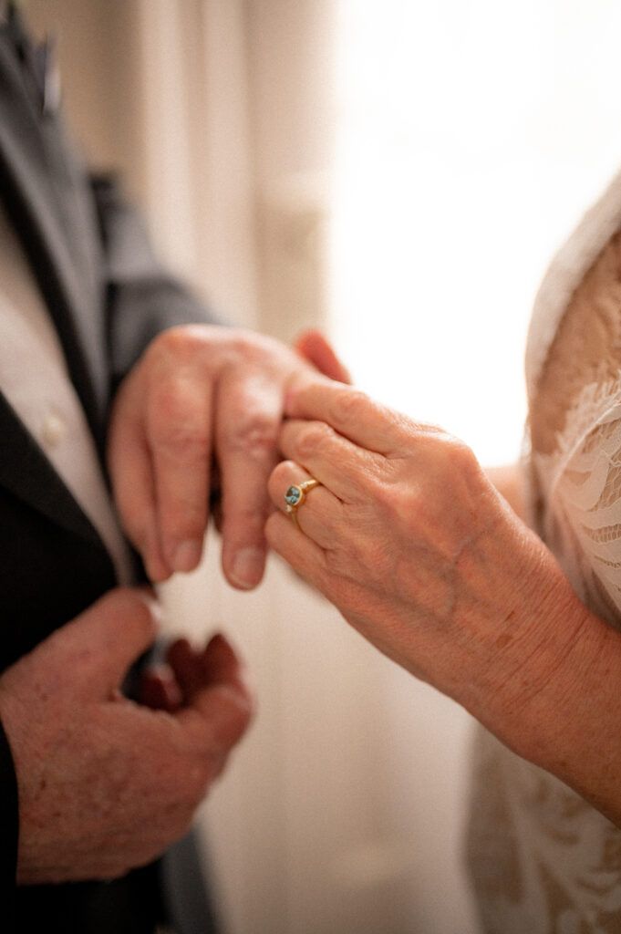 Senior Couple, bride and groom, exchange rings during their elopement at the Surf Hotel in Buena Vista, Colorado. Close up of hands.