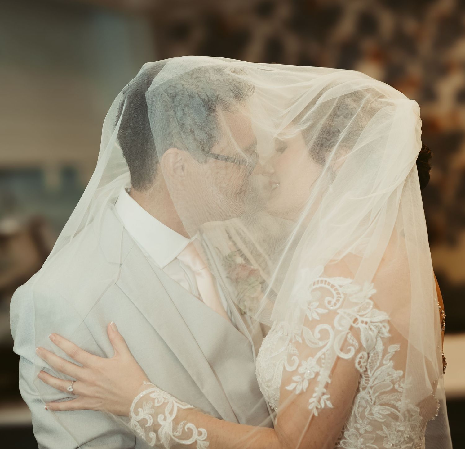 A romantic wedding moment showing a couple sharing a kiss under a delicate lace veil at their ceremony.