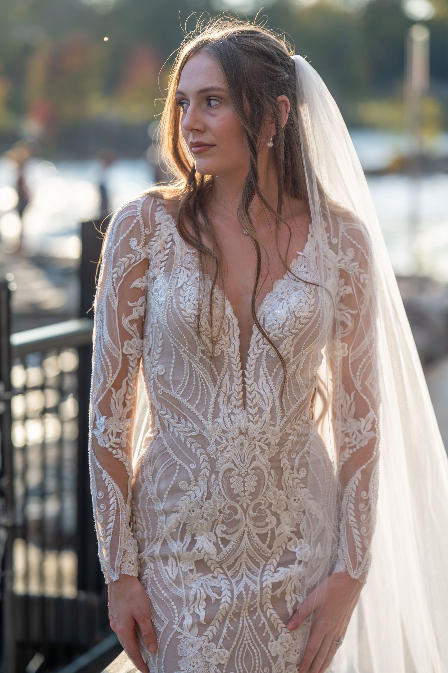 Elegant bridal portraits showcasing intricate lace details and flowing veil against an outdoor waterfront setting.