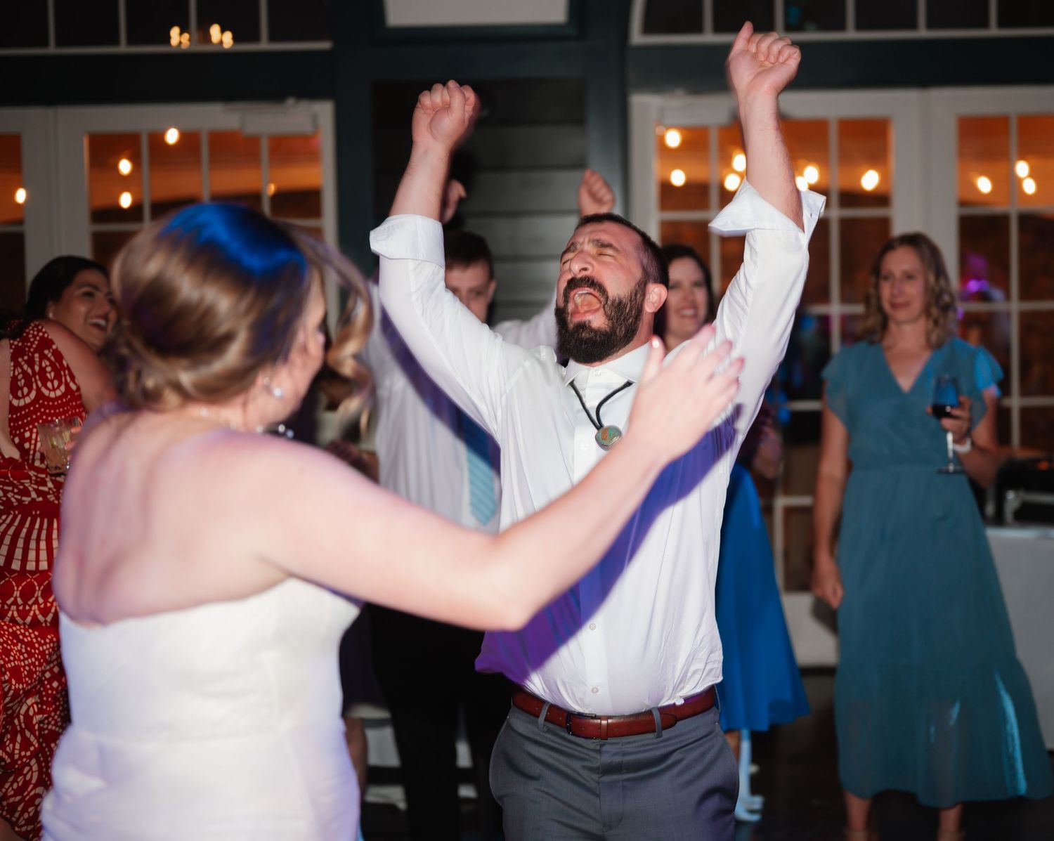 Wedding reception dance party with enthusiastic celebration on dance floor.