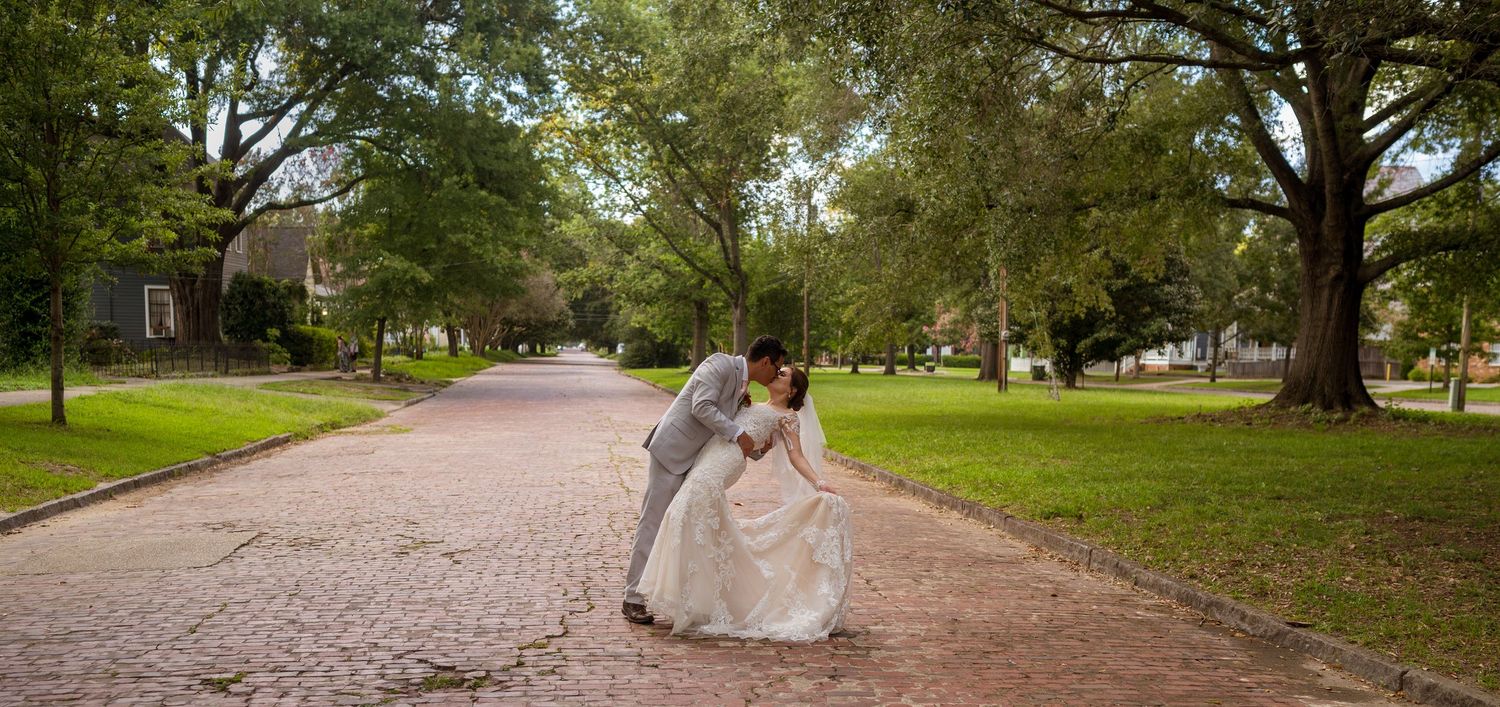 Tree-lined path with couple taking wedding photos in afternoon light.