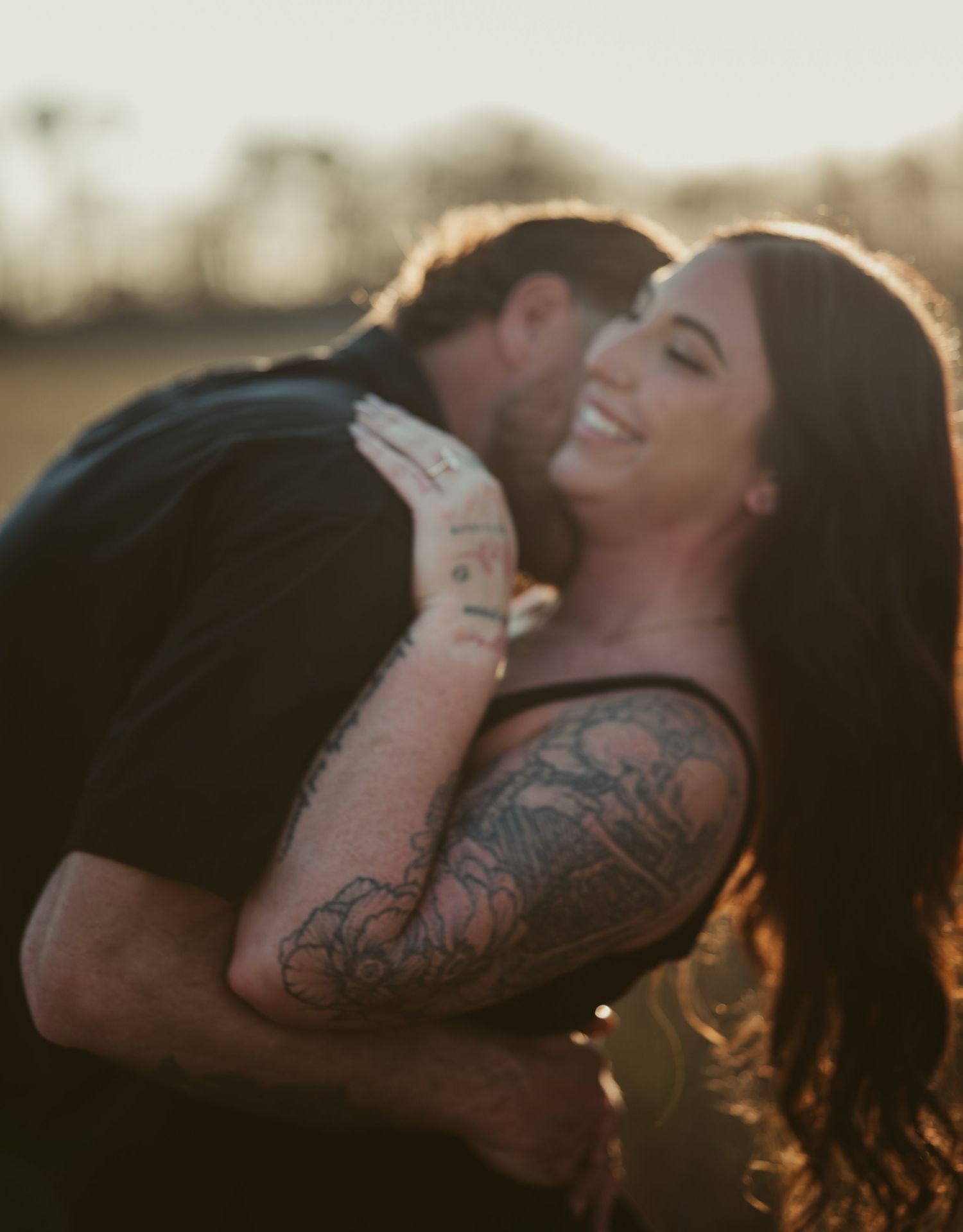 Silhouetted couple shares an intimate embrace against warm sunset sky.