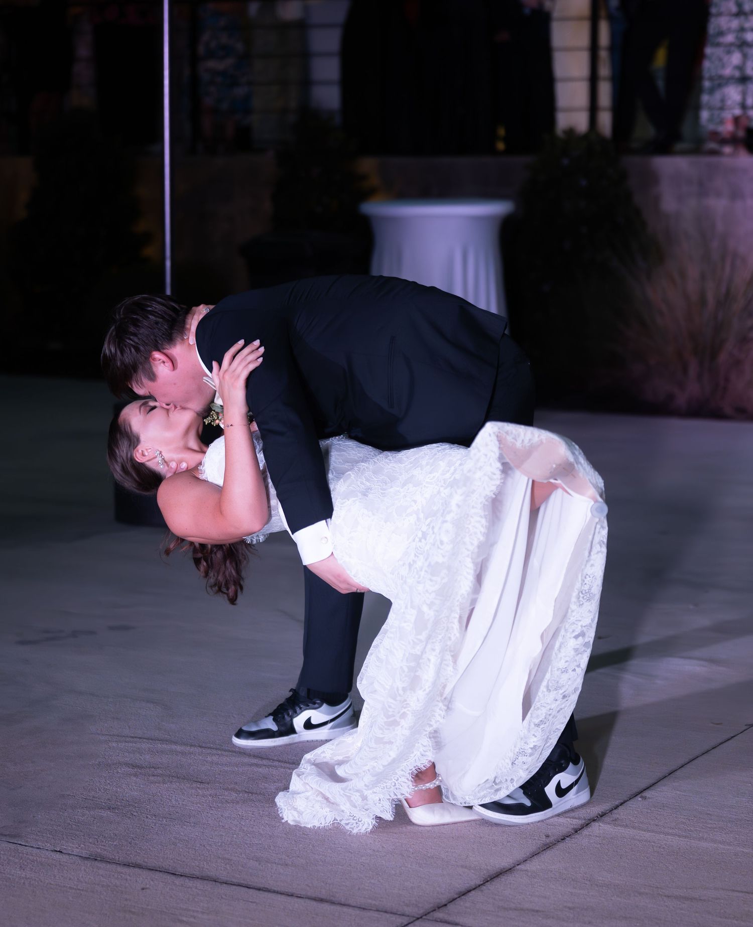 Wedding couple performing a dip dance move on outdoor patio.